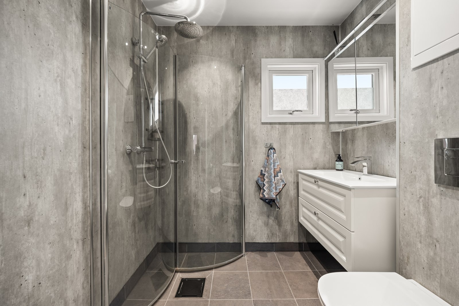 Badet inneholder dusjhjørne med innfellbare vegger, samt vegghengt innredning og toalett Galleribilde