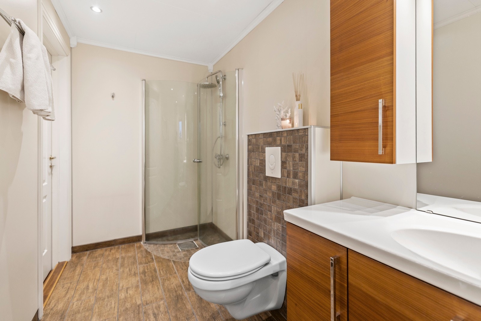 Dusjsonen har innfellbare glassdører som sparer plass, og er utstyrt med både tak- og hånddusj for fleksibel bruk. Det vegghengte toalettet med innebygd sisterne. Rommet har også opplegg for vaskemaskin og plass til tørketrommel. Galleribilde