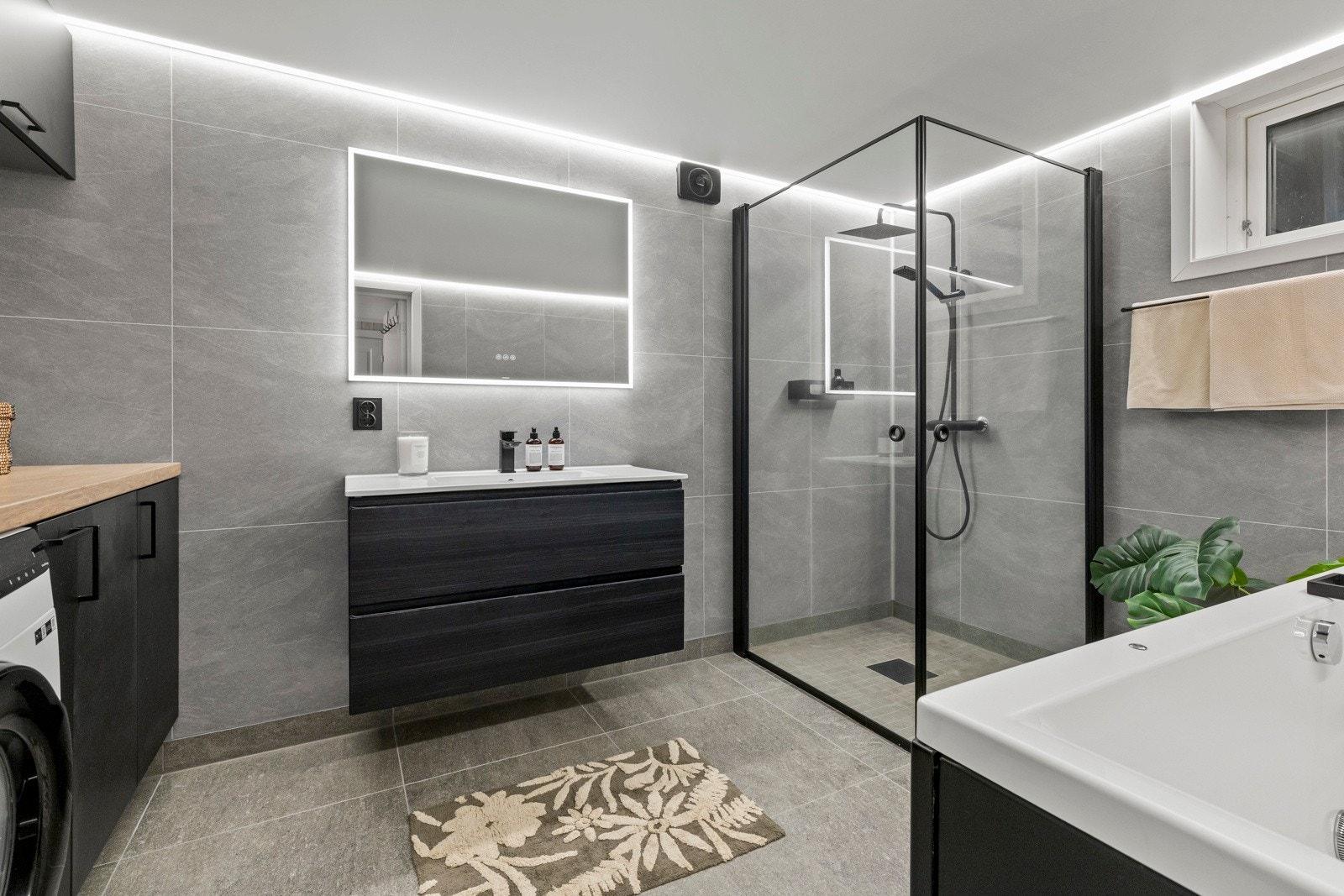 Moderne bad/vaskerom renovert i 2023 med flislagt gulv med varme og store, tidsriktige fliser på veggene. Galleribilde