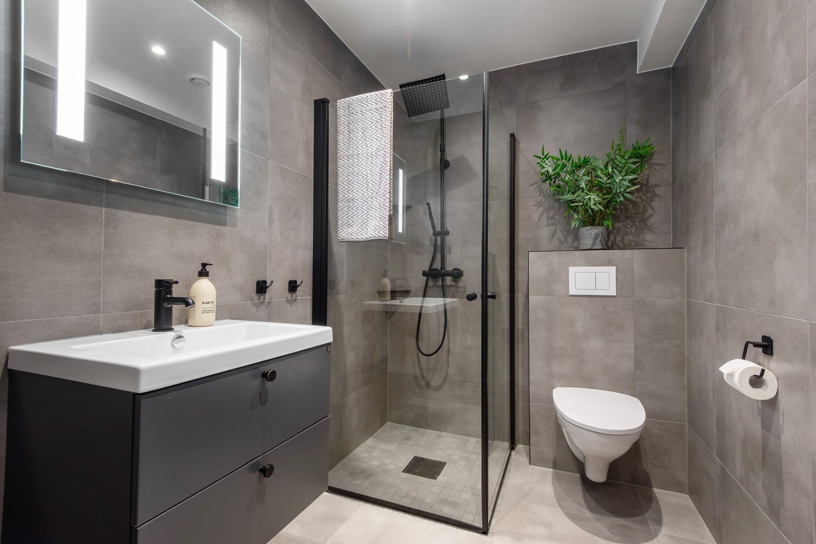 Badet i første etasje fremstår tidløst og stilrent, med grå fliser og behagelig gulvvarme. Galleribilde