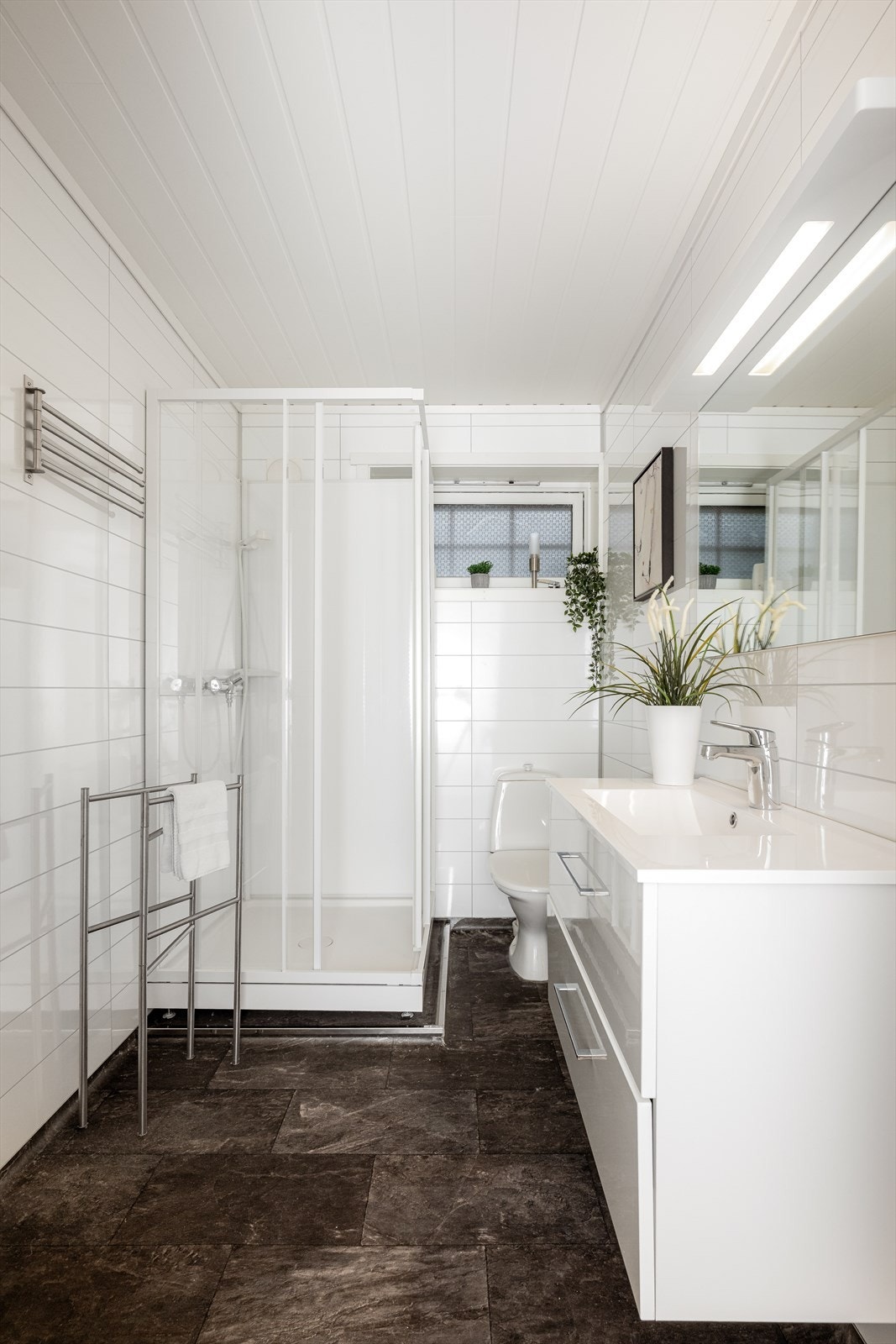 Badet i kjelleretasjen er oppgradert i 2018 og har belegg på gulv med varmekabler. Badet har en moderne innredning med dype skuffer og heldekkende servant, samt speil med overlys. Badet er også innredet med dusjkabinett og toalett. Galleribilde