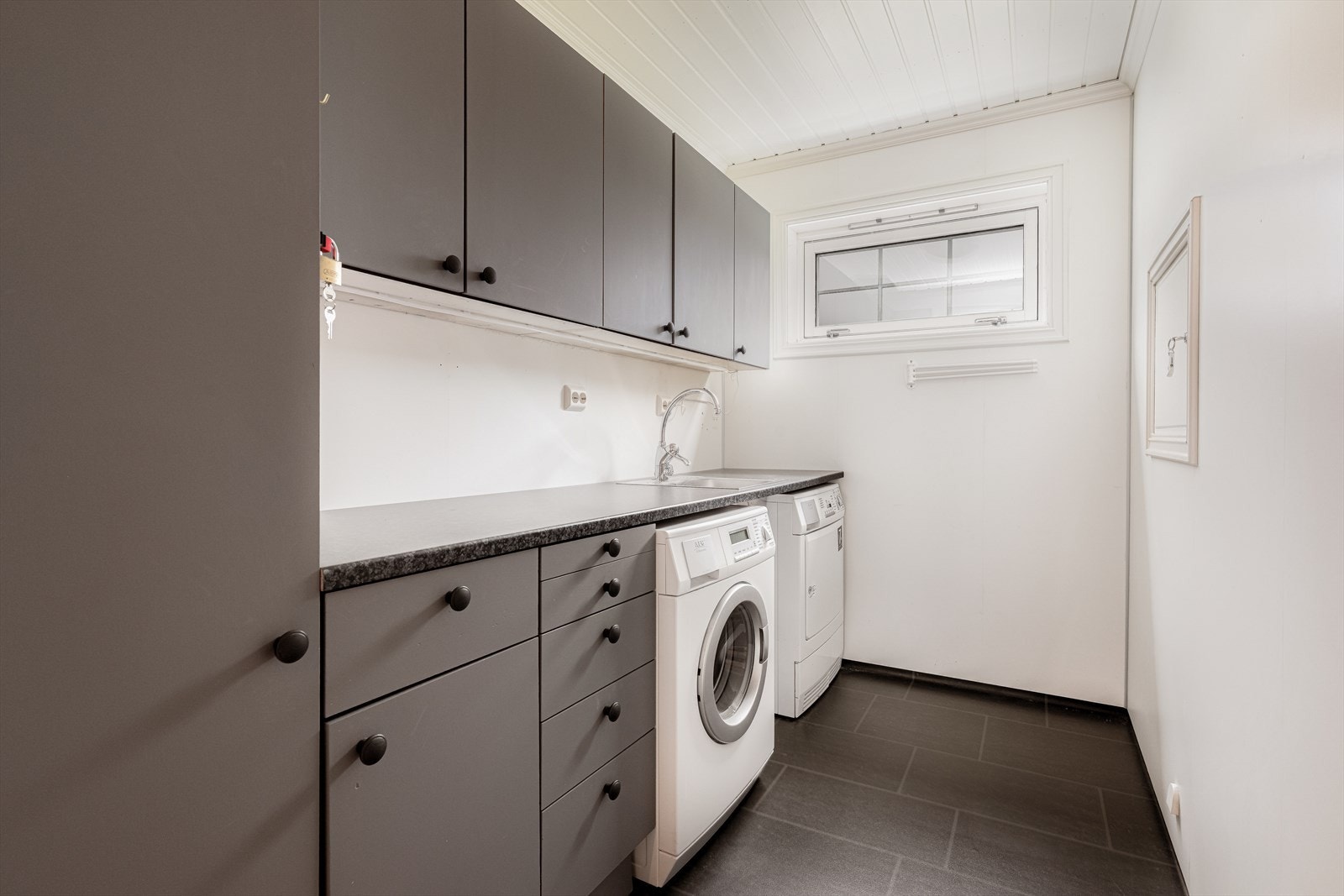 Boligen har eget, praktisk innredet vaskerom i 1. etasje fra 2006. Her har man gode arbeidsforhold med god benkeplass, nedfelt vaskekum og god oppbevaringsplass i over- og underskap. Galleribilde