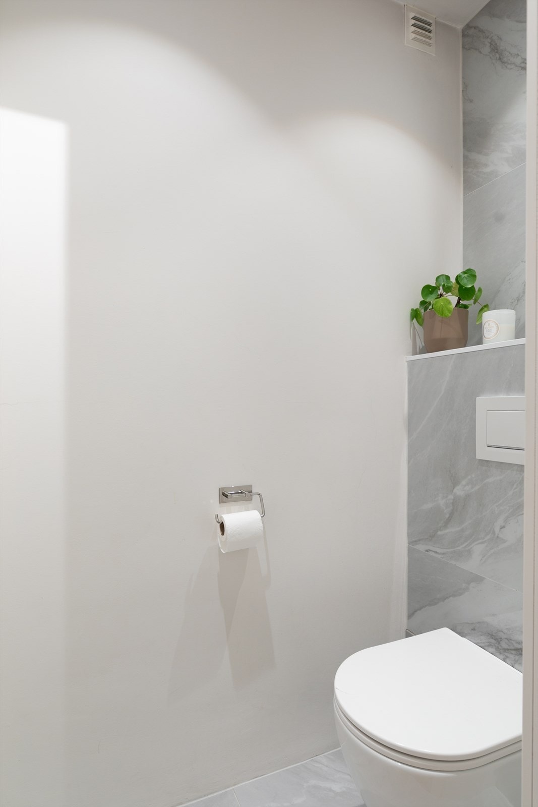 Vegg i vegg med badet ligget et separat toalettrom med veggmontert wc. Galleribilde