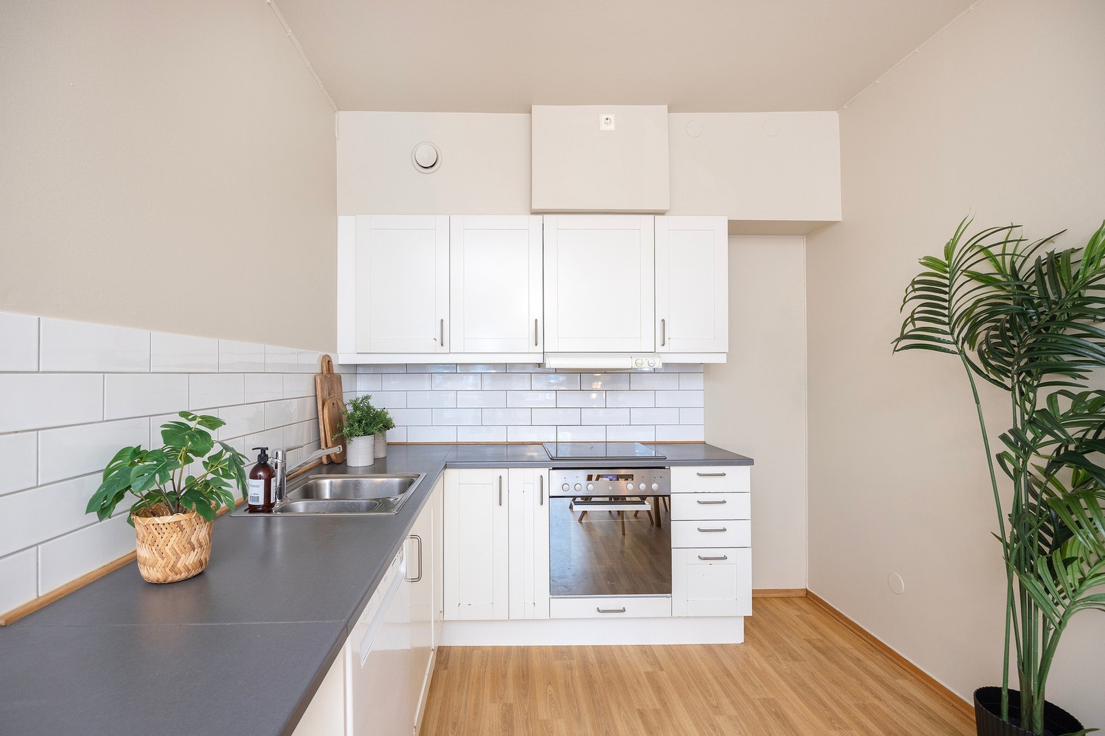 Sigdal kjøkkeninnredning med hvite fronter, laminert benkeplate, lys under overskap, ventilator med platetopp og stålkum med blandebatteri. Plass til kjøleskap og vaskemaskin. Galleribilde