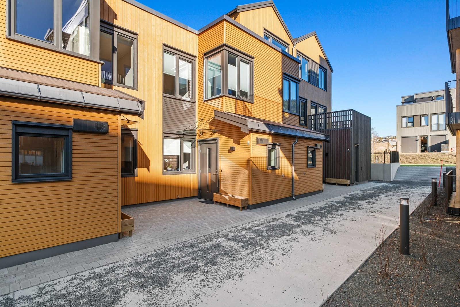 Flott fasade med varme trefarger og store vinduer som gir godt med lysinnslipp. Galleribilde