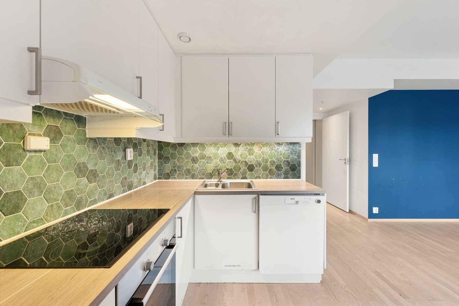 Kjøkkeninnredning med under-/overskap og slette fronter, benkeplater av laminat med nedfelt kum i rustfritt stål og ett-greps blandebatteri. Galleribilde