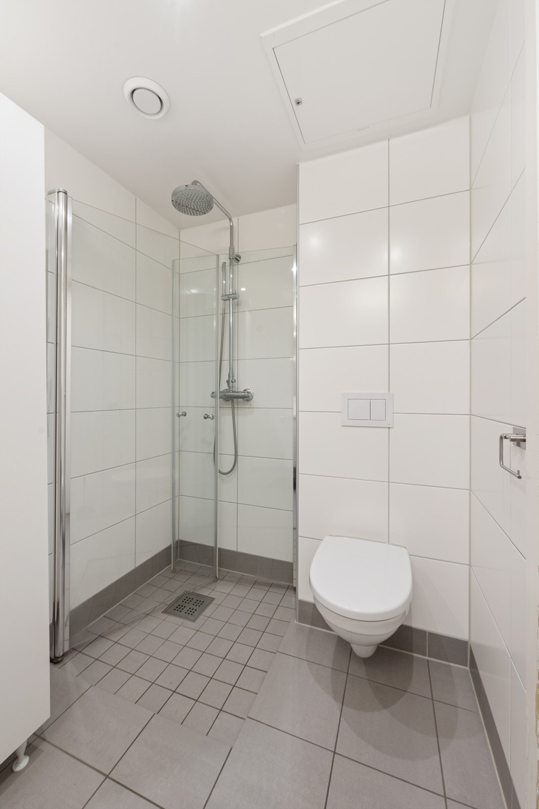 Badet er innredet med servantskap med ett-greps blandebatteri, veggskap, avskjermet dusjhjørne med glass, blandebatteri og dusjgarnityr. Galleribilde