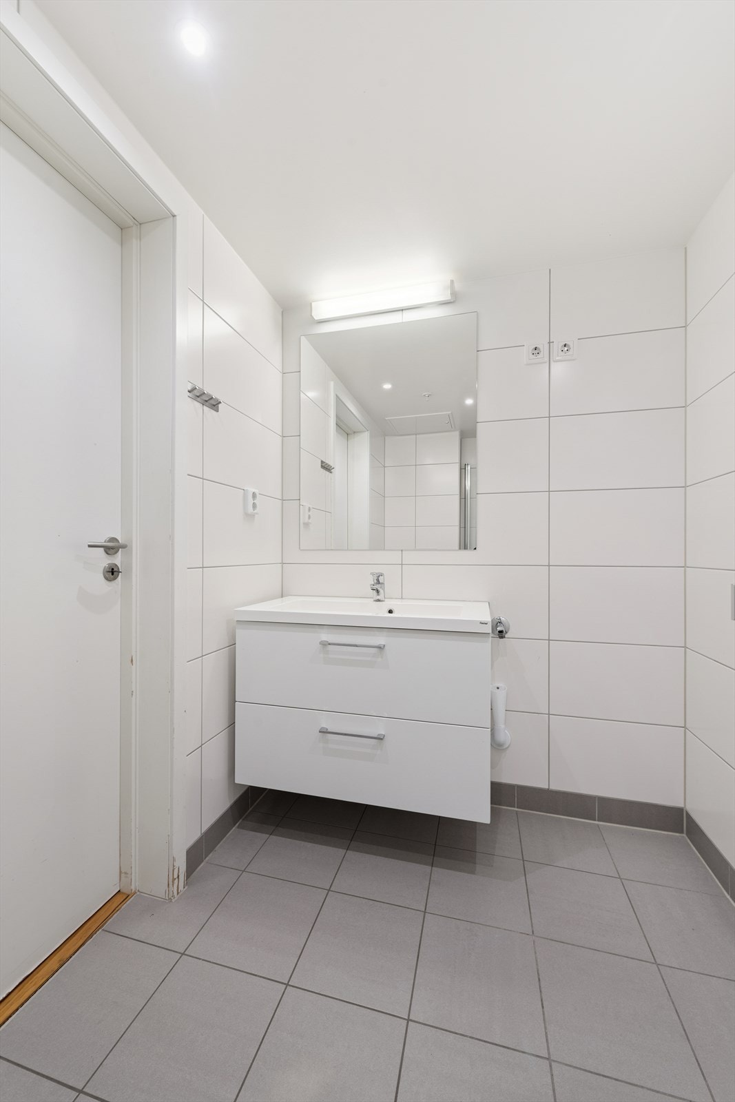 Badet fremstår som moderne og delikat, med lyse fliser og en tidløs utforming. Galleribilde