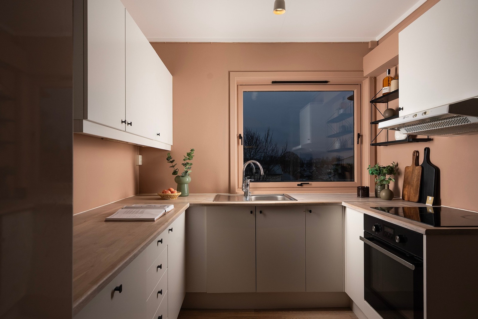 På kjøkkenet har du lyse slette fronter på innredningen og svarte detaljer i håndtak og integrert stekeovn og platetopp Galleribilde