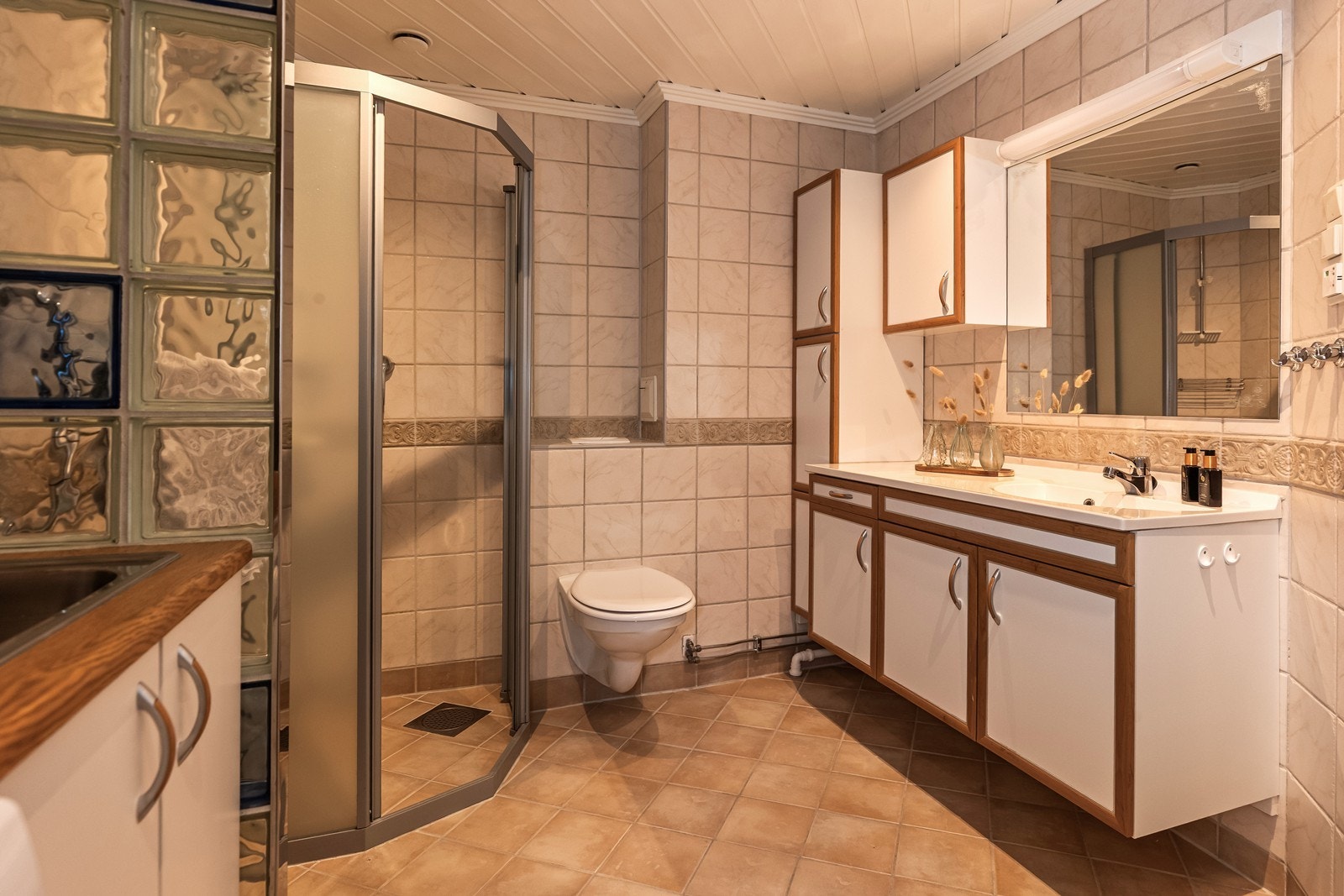 Innholdsrik baderomsinnredning, vegghengt toalett og dusjnisje. Galleribilde