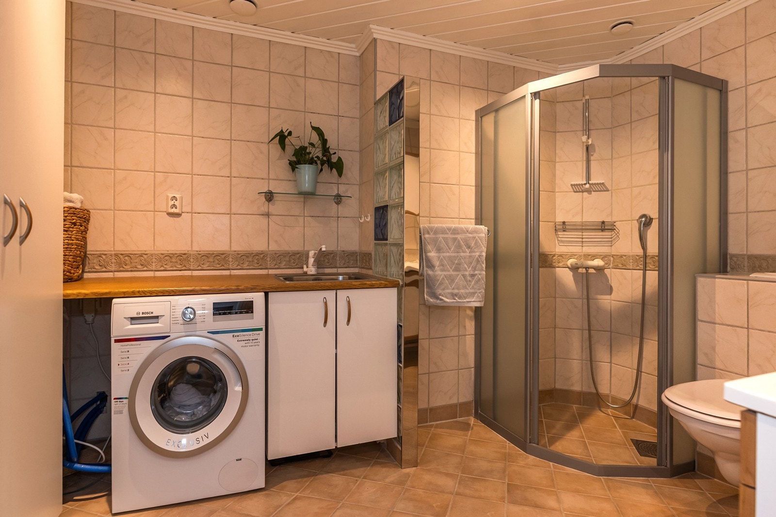 Badet er flislagt og har elektriske gulvvvarme. Utvidet i forhold til opprinnelig størrelse slik at det nå er et romslig bad med vaskeromsløsning. Galleribilde