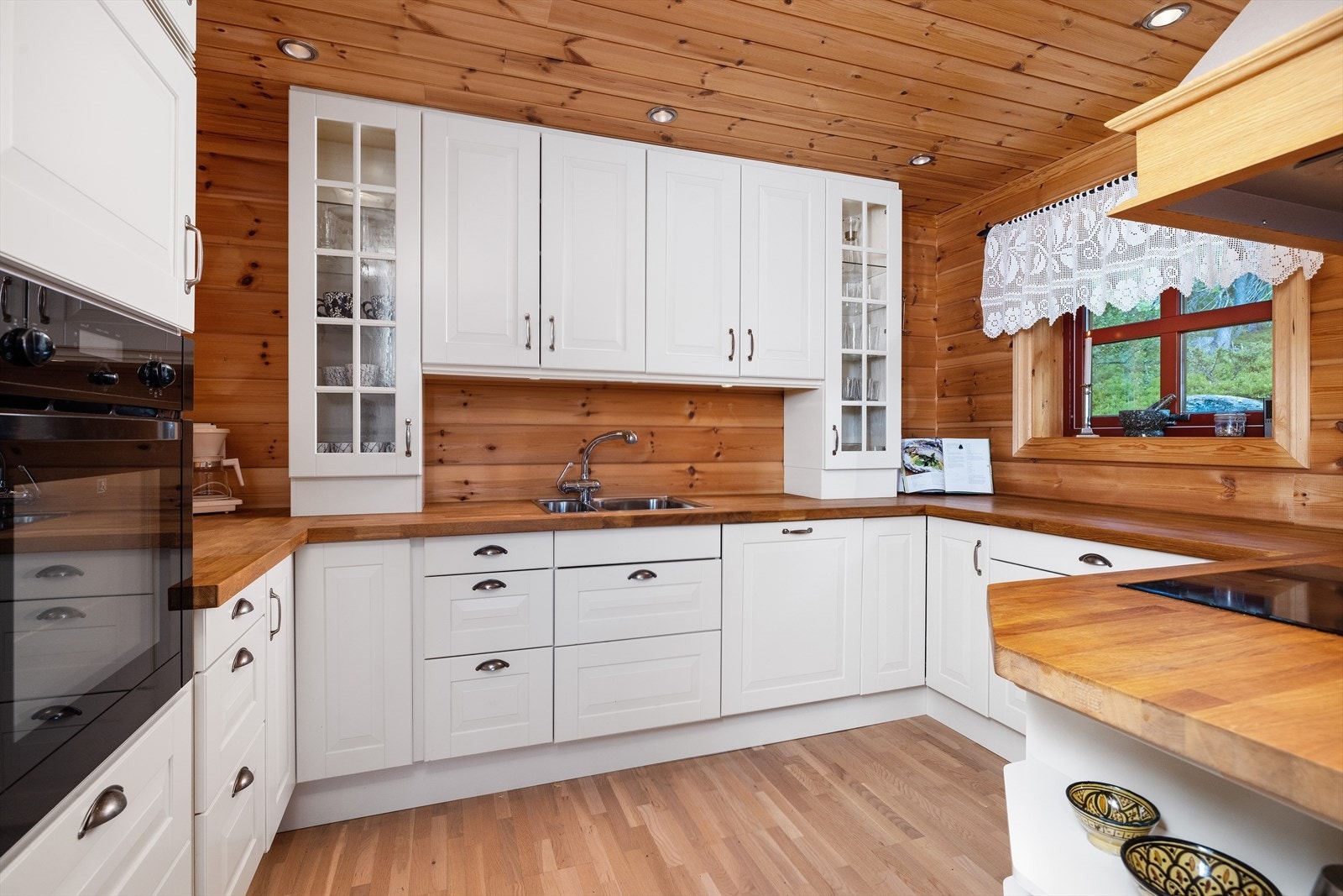 Kjøkkenet er hvitmalt med profilerte fronter, benkeplate i heltre og integrerte hvitevarer. Galleribilde