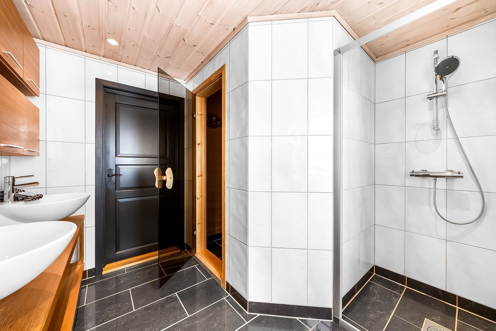 Moderne bad med flislagt dusj og badstue. Lyst trepanel i taket skaper en varm og innbydende atmosfære. Galleribilde
