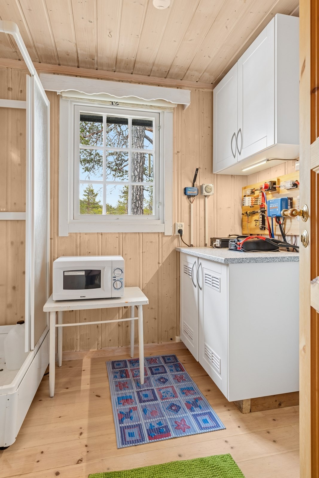 Enkelt bad med dusjkabinett, servant, skapinnredning og propandrevet vannvarmer. Rommet er ikke bygget som et våtrom og har ikke sluk Galleribilde