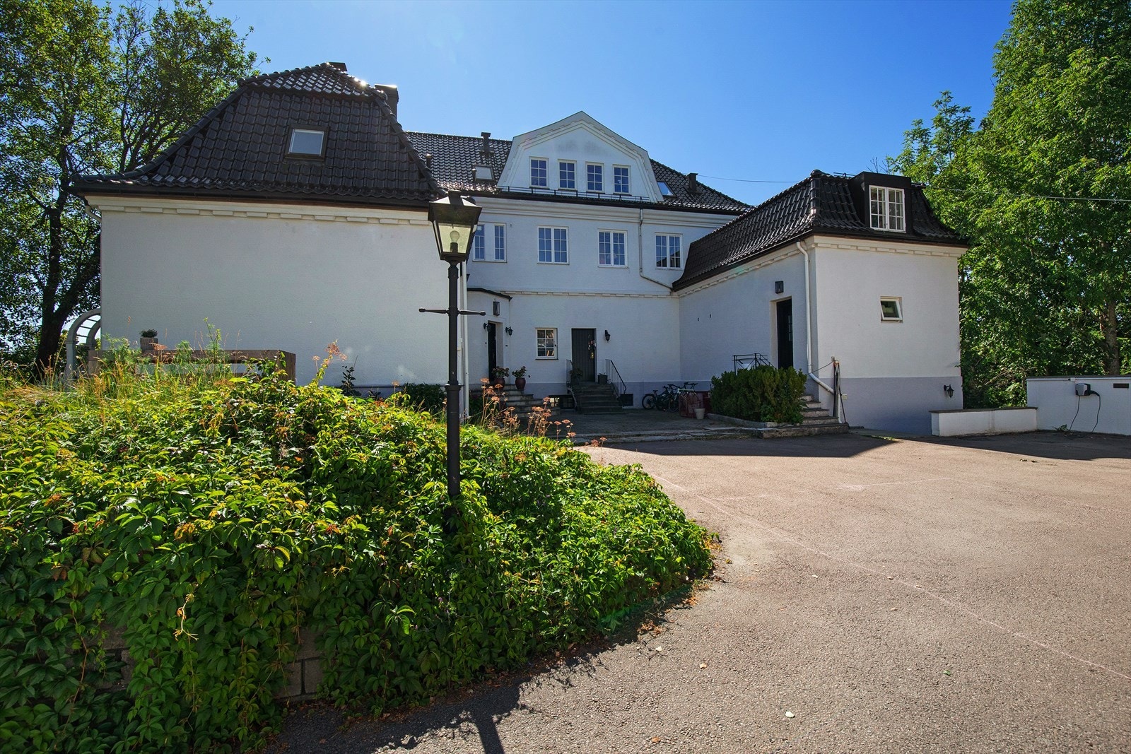 På forsiden ligger byggets inngangsparti med steinsatt uteplass, og adkomst via trapp. Galleribilde