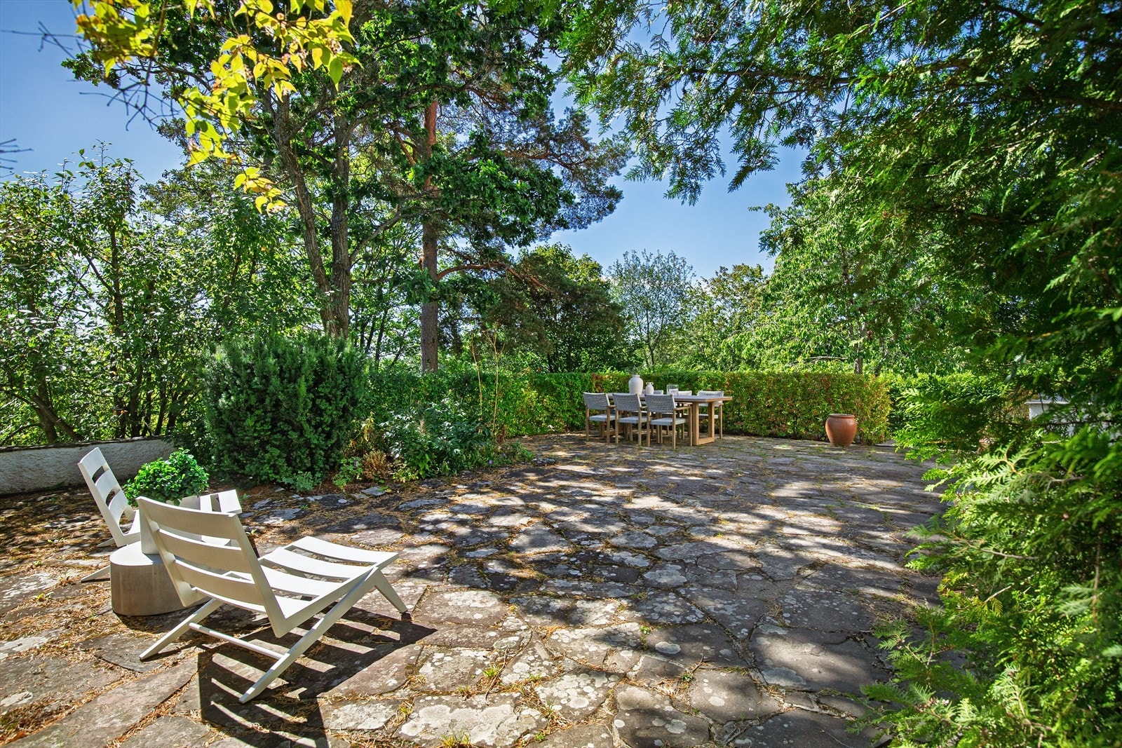 Den åpne markterrassen kan romme det meste av møblement. De frodige trærne som omkranser eiendommen gir god skjerming til uteområdet. Galleribilde