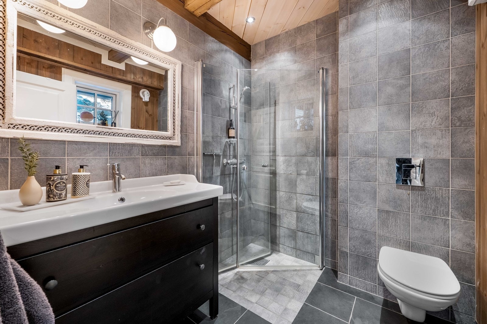 Badet i hovedetasjen: Flislagt og moderne bad fra byggeår 2013 med gulvvarme og mekanisk avtrekk. Downlights i himlingen og vegghengte lamper over speilet. Galleribilde