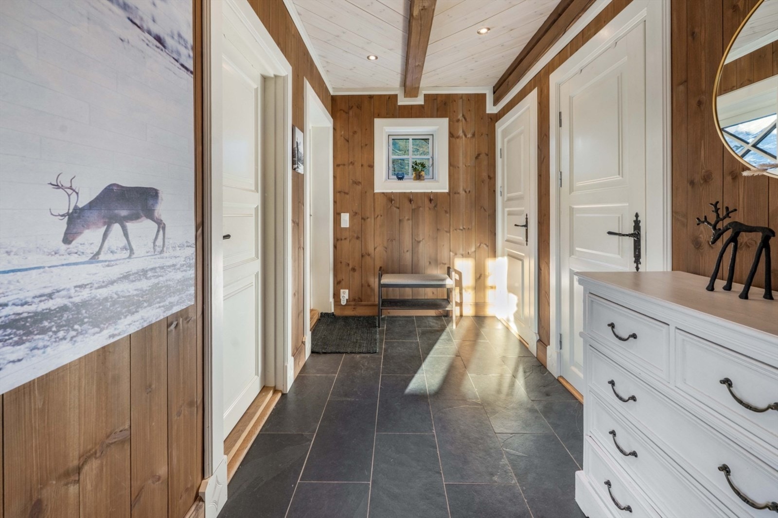 Innbyende entré som gir et godt førsteinntrykk av hytta. Gangen har flislagt gulv med gulvvarme og downlights i taket. Galleribilde