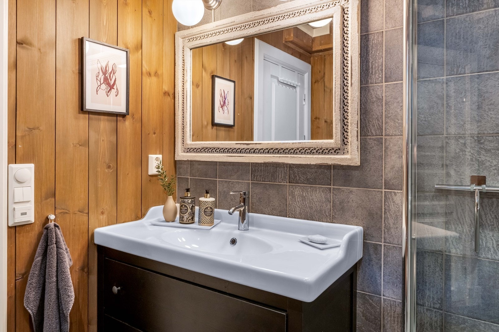 Badet er utstyr med servant med innredning, speil, dusjhjørne og vegghengt toalett. Galleribilde