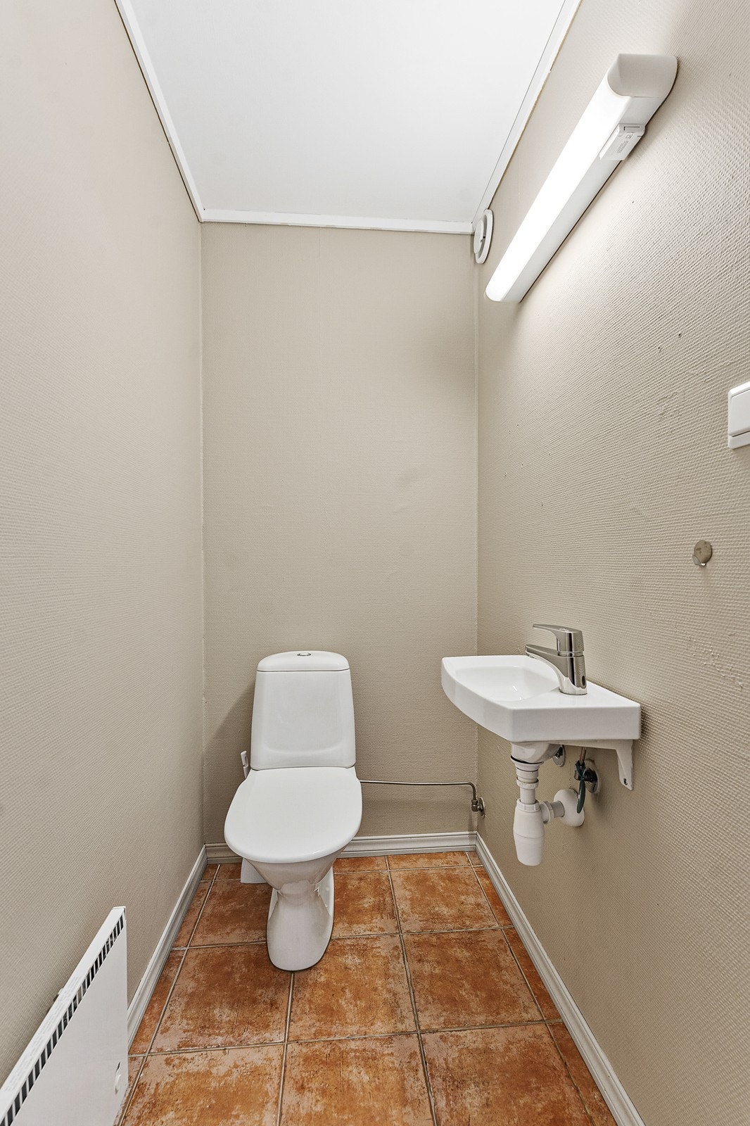 Det er også et praktisk toalett i leiligheten, med fliser på gulvet. Galleribilde