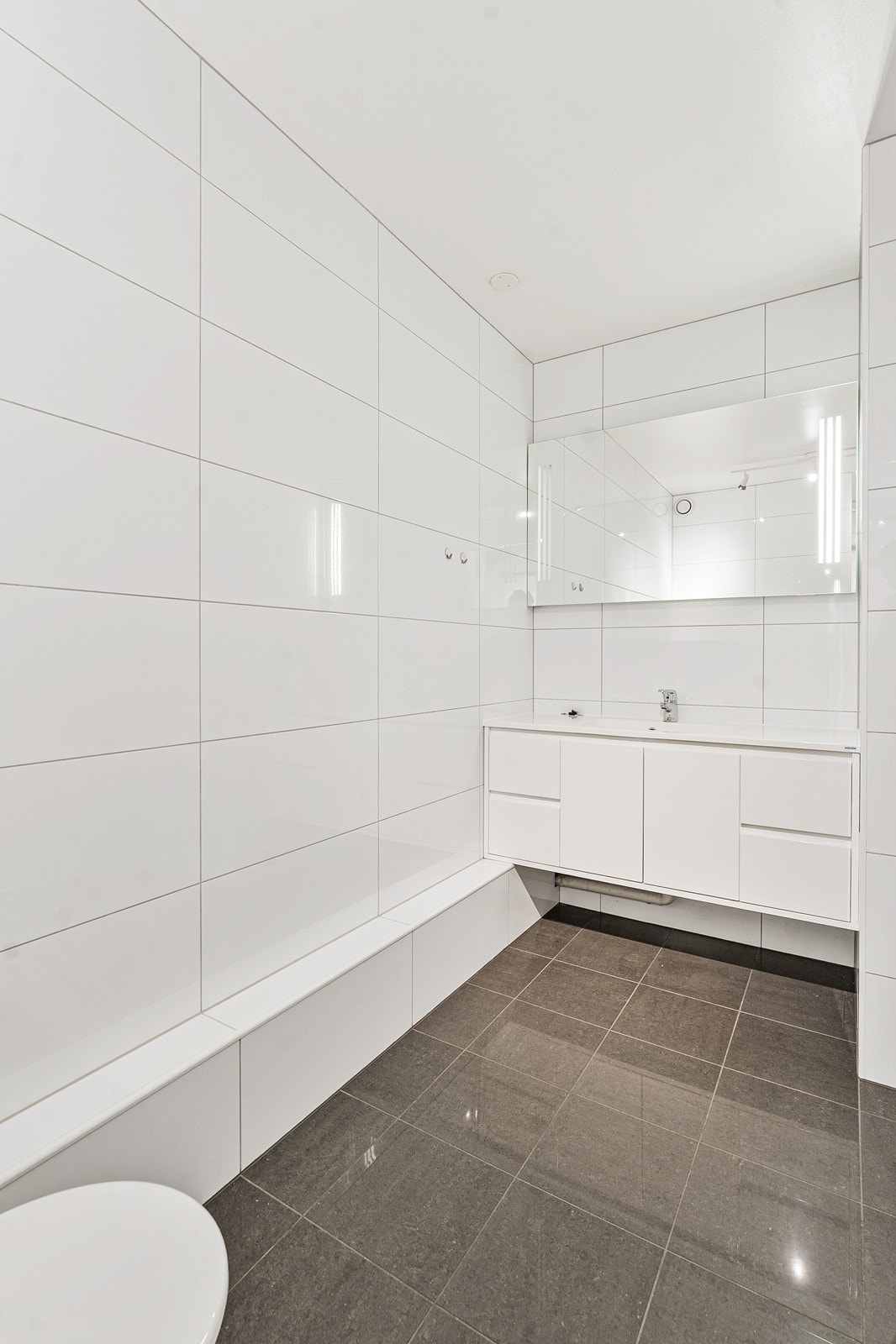 Badet er innredet med servant i møbel, vegghengt toalett og eget dusjrom. Galleribilde