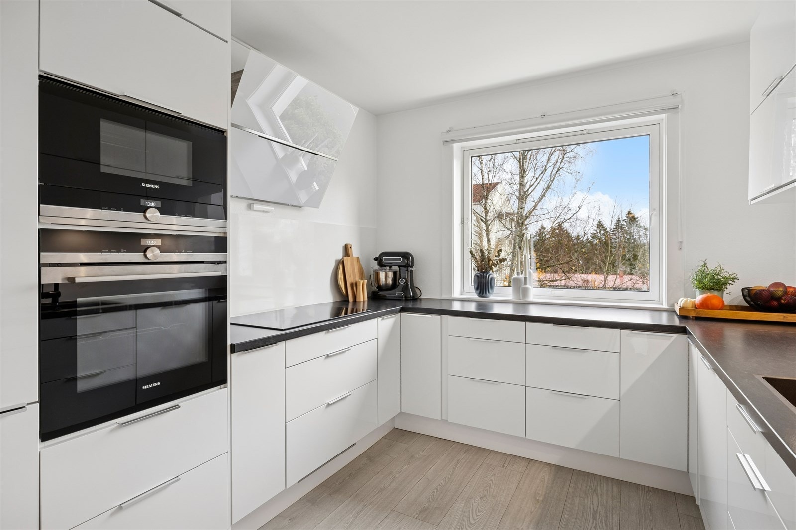 Kjøkken med lyse høyglansfronter, laminert benkeplate og nedfelt oppvaskkum. Galleribilde