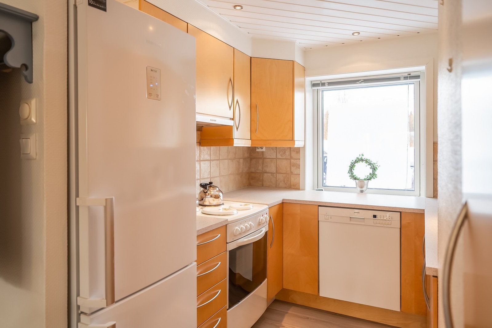 Pent og velholdt kjøkken med med glatte fronter og laminat benkeplate. Galleribilde