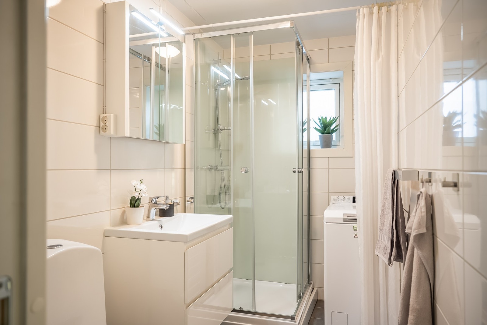 Badet inneholder toalett, servantskap med servant, opplegg for vaskemaskin og dusjkabinett. Galleribilde