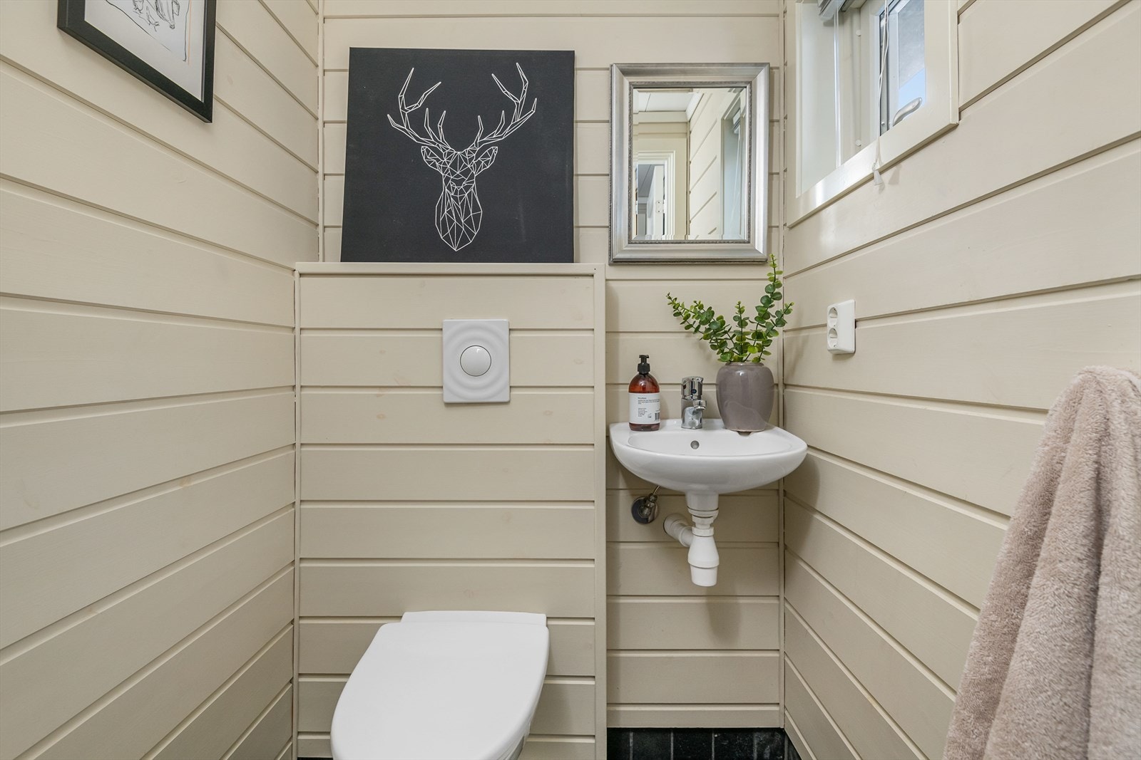 Leiligheten har i tillegg et wc-rom med fliser på gulv og panel på veggene. Rommet er innredet med vegghengt toalett og servant. Galleribilde