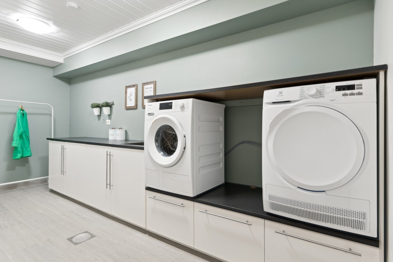 Vaskerom i kjeller. Her er det god lagring på benkeplass, skap og skuffer. Her er det opplegg for vaskemaskin og tørketrommel. Galleribilde