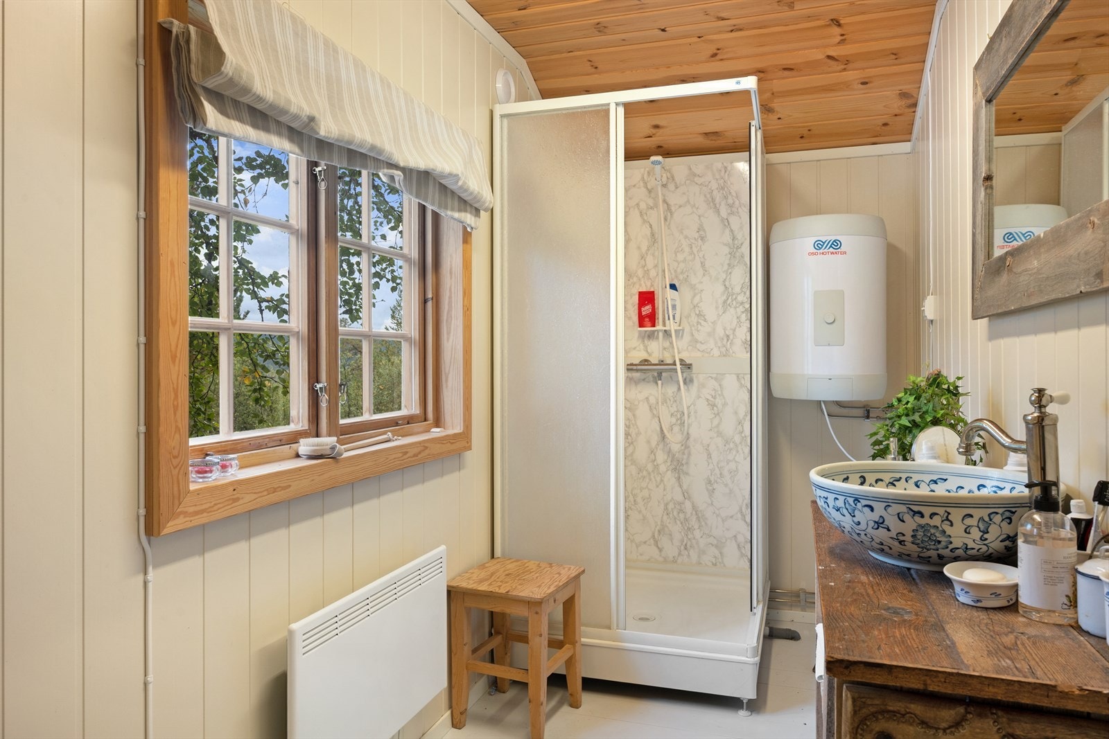 Enkelt innredet sanitærrom med servant, dusjkabinett og forbrenningstoalett. Galleribilde