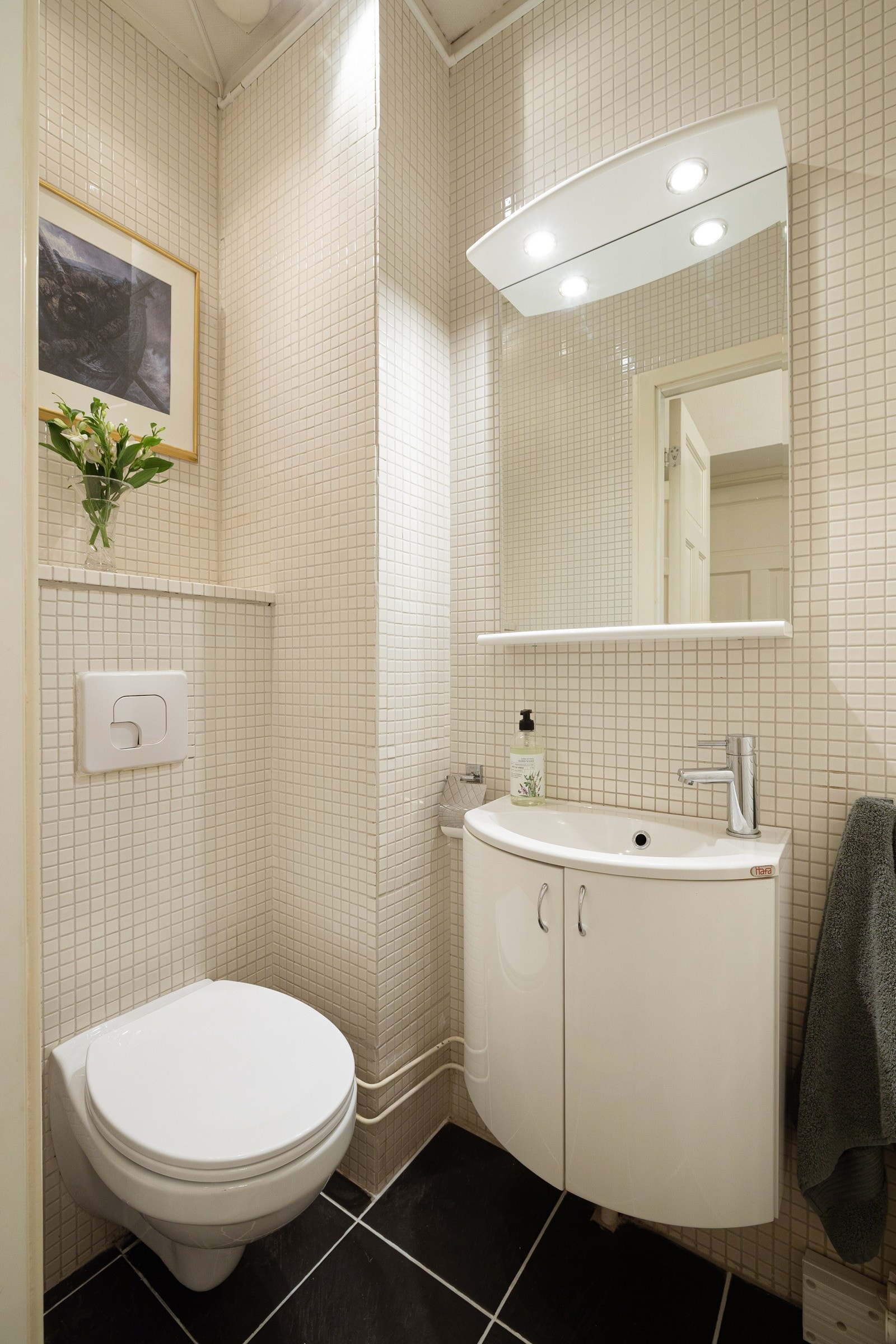 Toalettrommet, oppusset i 2006/07 og har mørke fliser på gulvet, keramiske fliser på veggene, servantskap, speil med belysning og vegghengt toalett Galleribilde