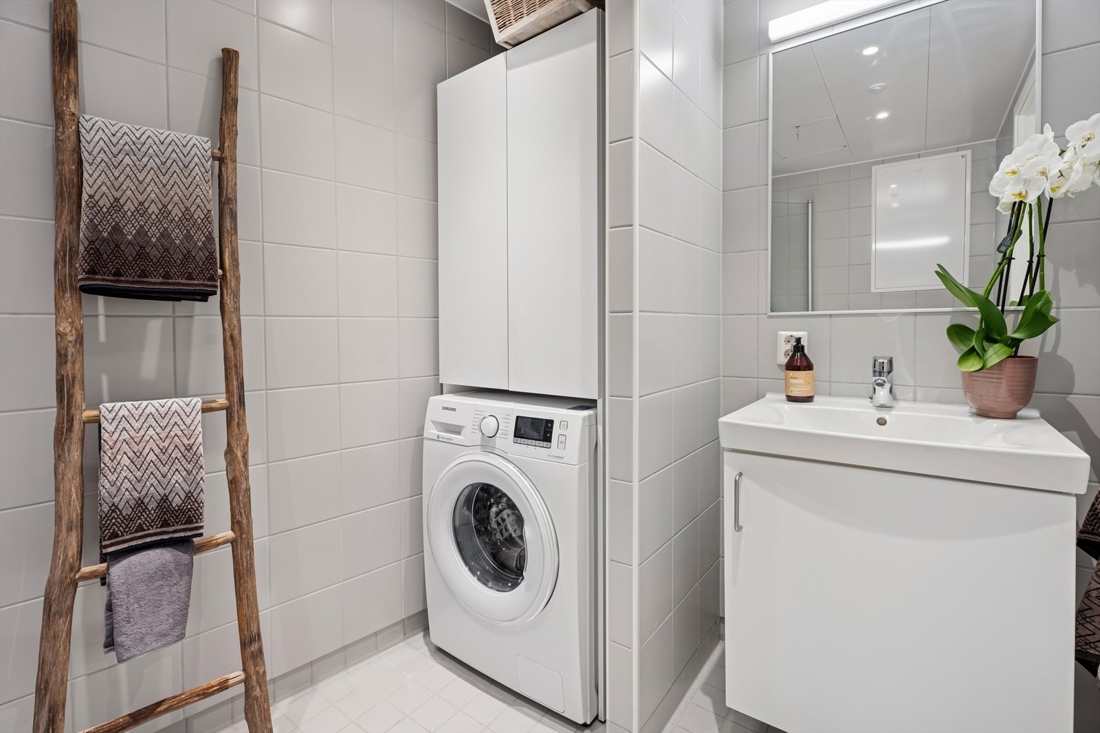 Rommet er flislagt, har behagelig gulvvarme og egen nisje for vaskemaskin og tørketrommel. Galleribilde