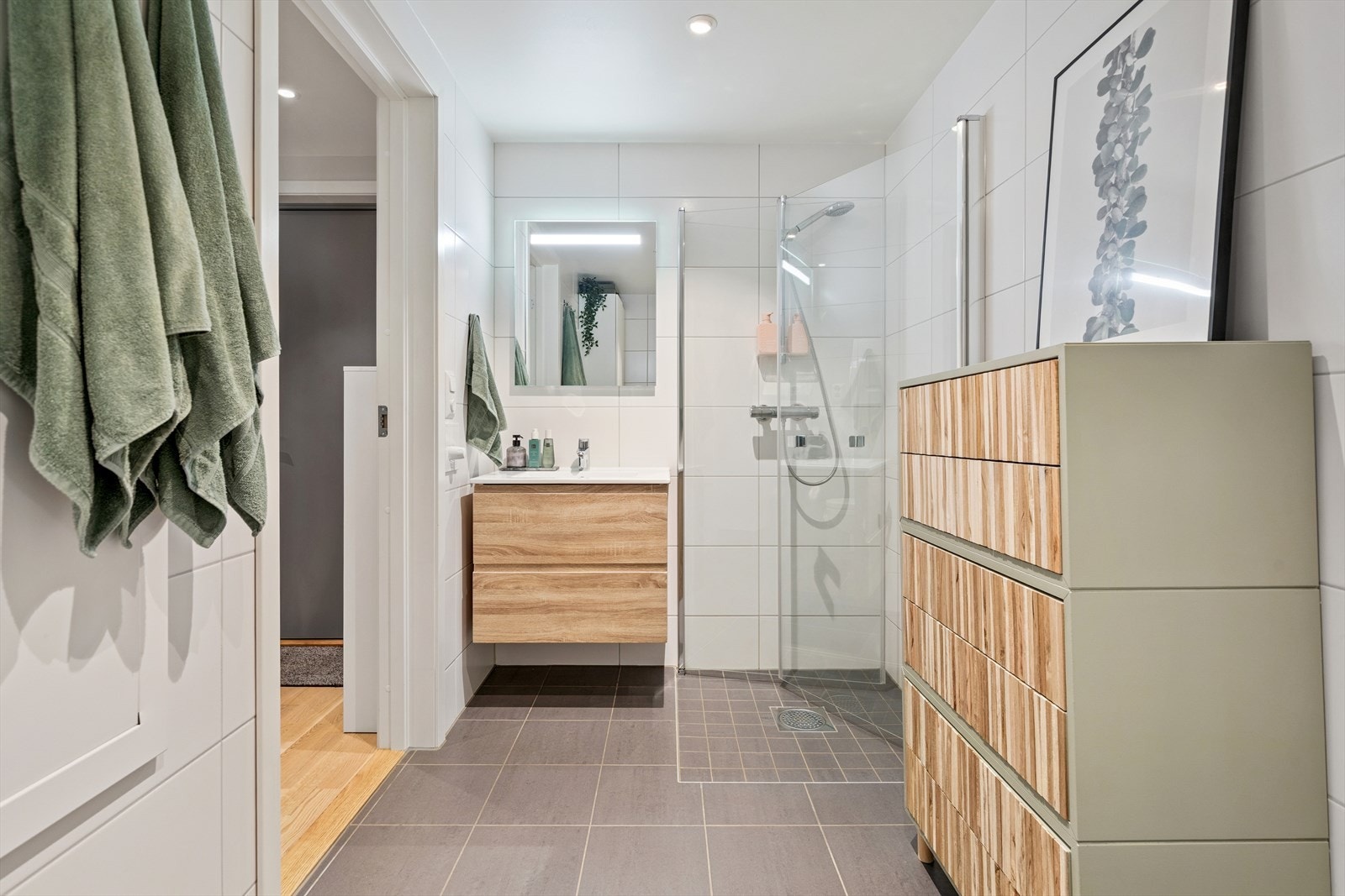 Flislagt baderom med vannbåren gulvvarme og downlights. Badet er utstyrt med servant i baderomsinnredning og speil med belysning. Galleribilde