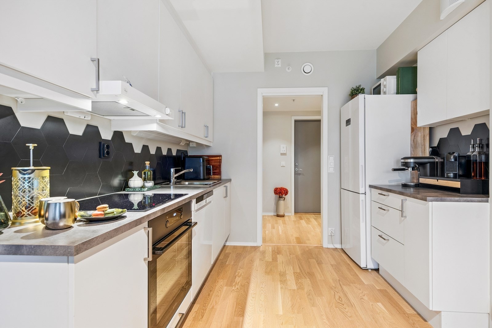 Hvit, slett kjøkkeninnredning med laminert benkeplate. Galleribilde