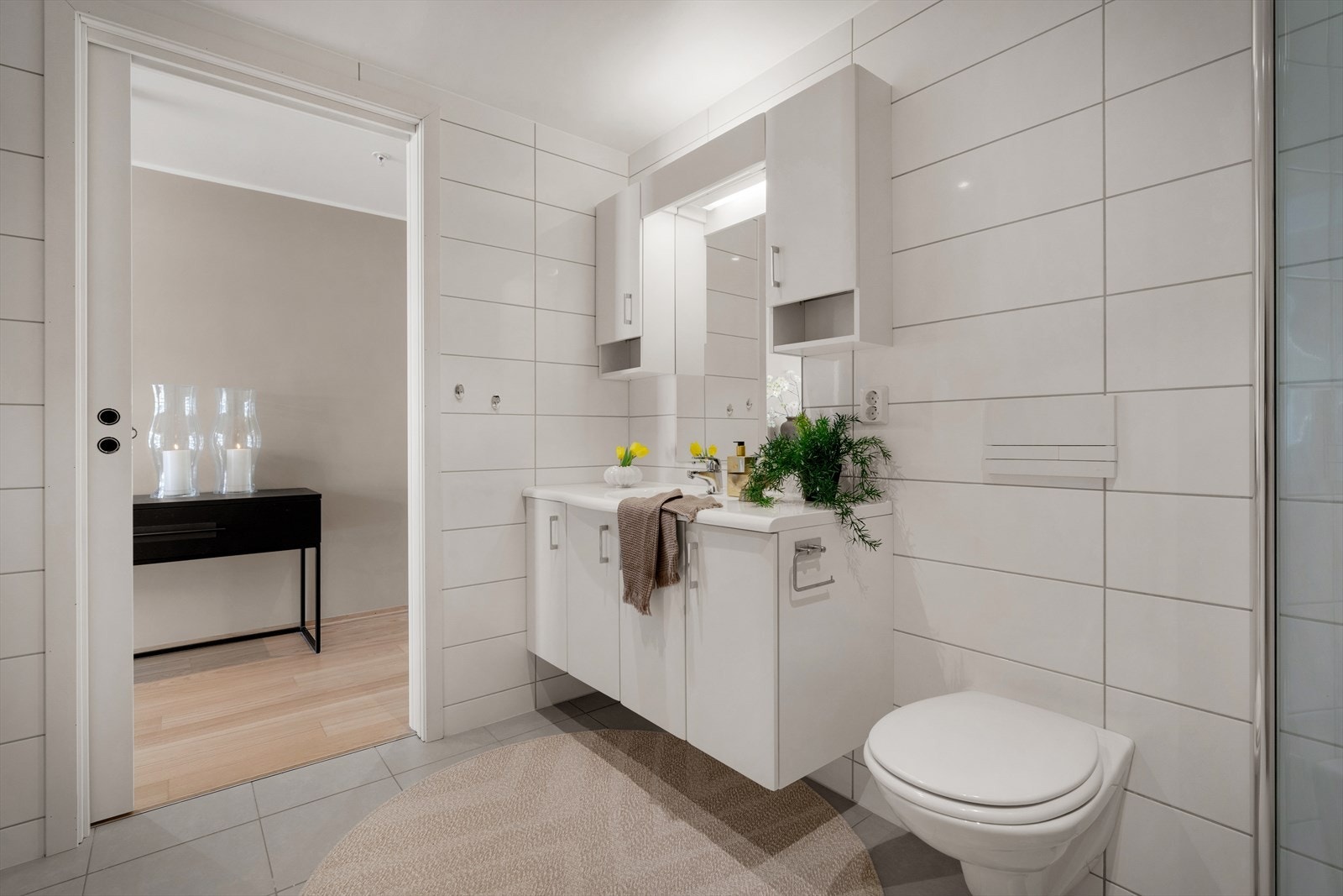 - Badet er innredet med servantmøbel, speil med belysning, vegghengt toalett og dusjhjørne med innfellbare glassdører - Galleribilde