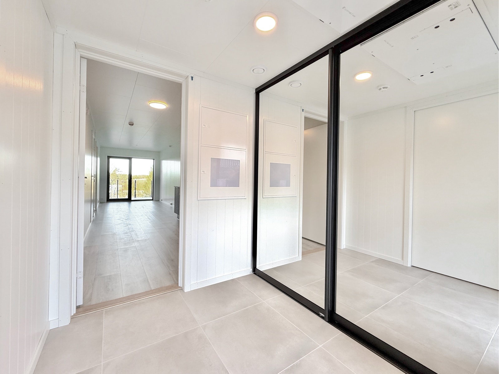 Lys og romslig entré med flislagt gulv og speilskyvedørsgarderobe Galleribilde