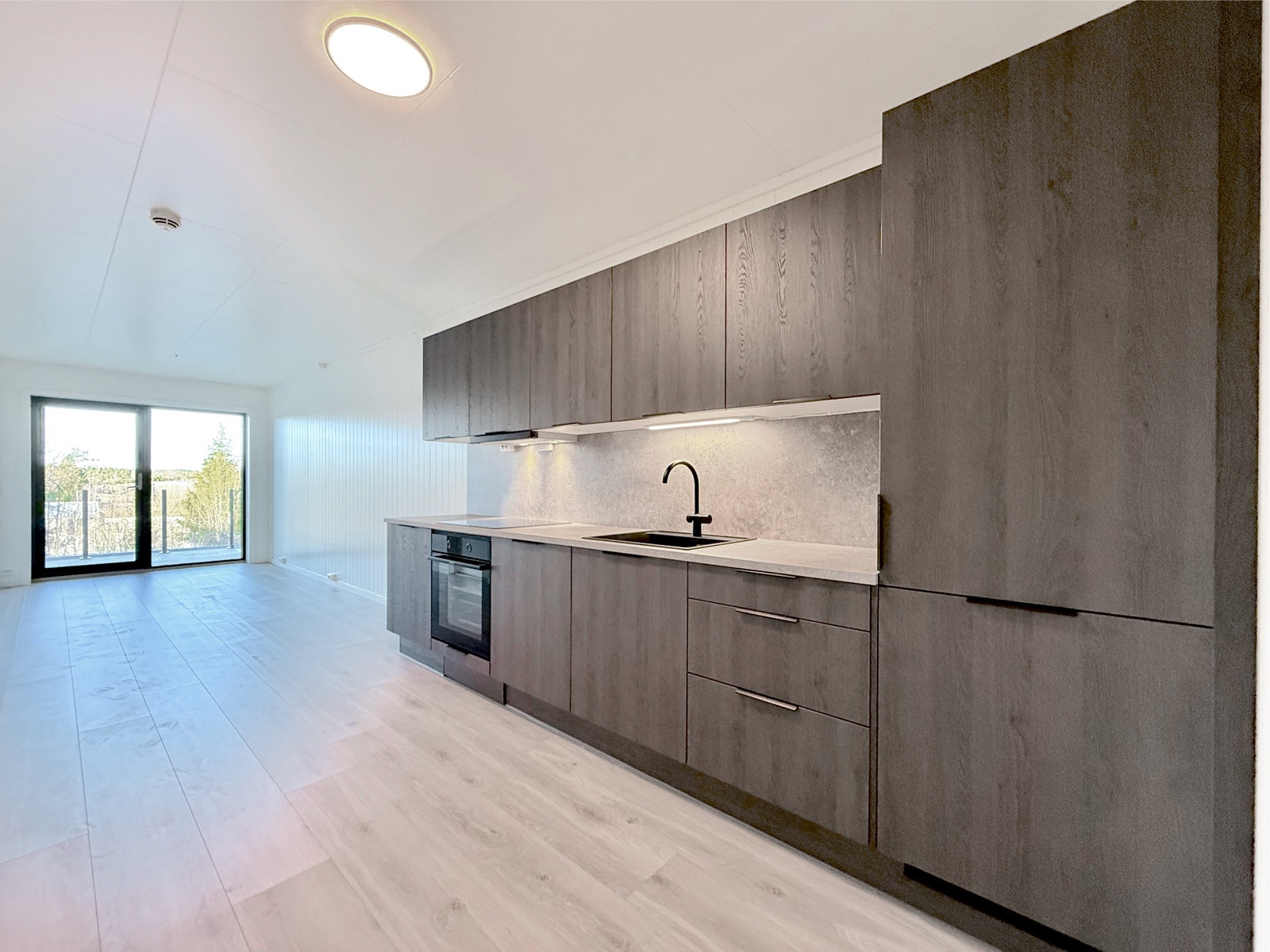 Åpent allrom med moderne kjøkken og god plass til stuemøbler mot terrassen. Galleribilde