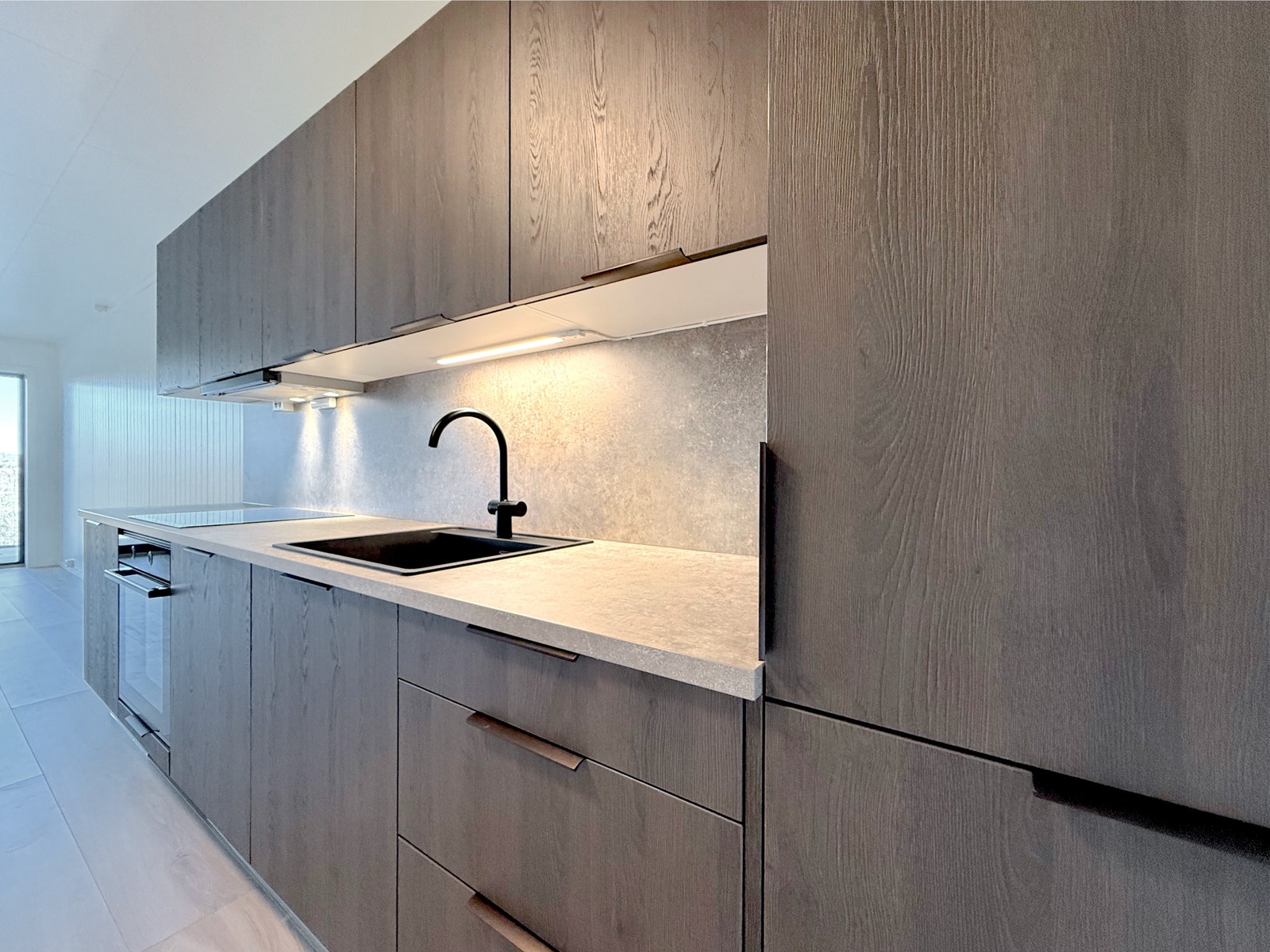 Kjøkkenløsning med integrerte skap og sorte detaljer Galleribilde