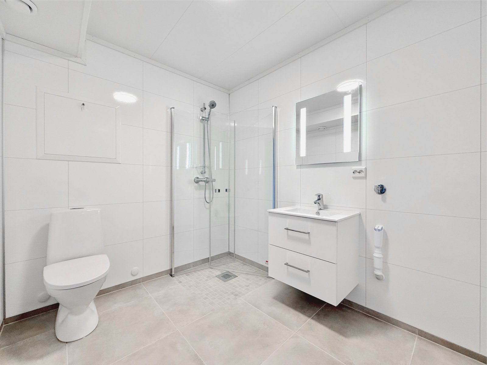 Baderom med toalett, dusjhjørne og servant med speilskap Galleribilde