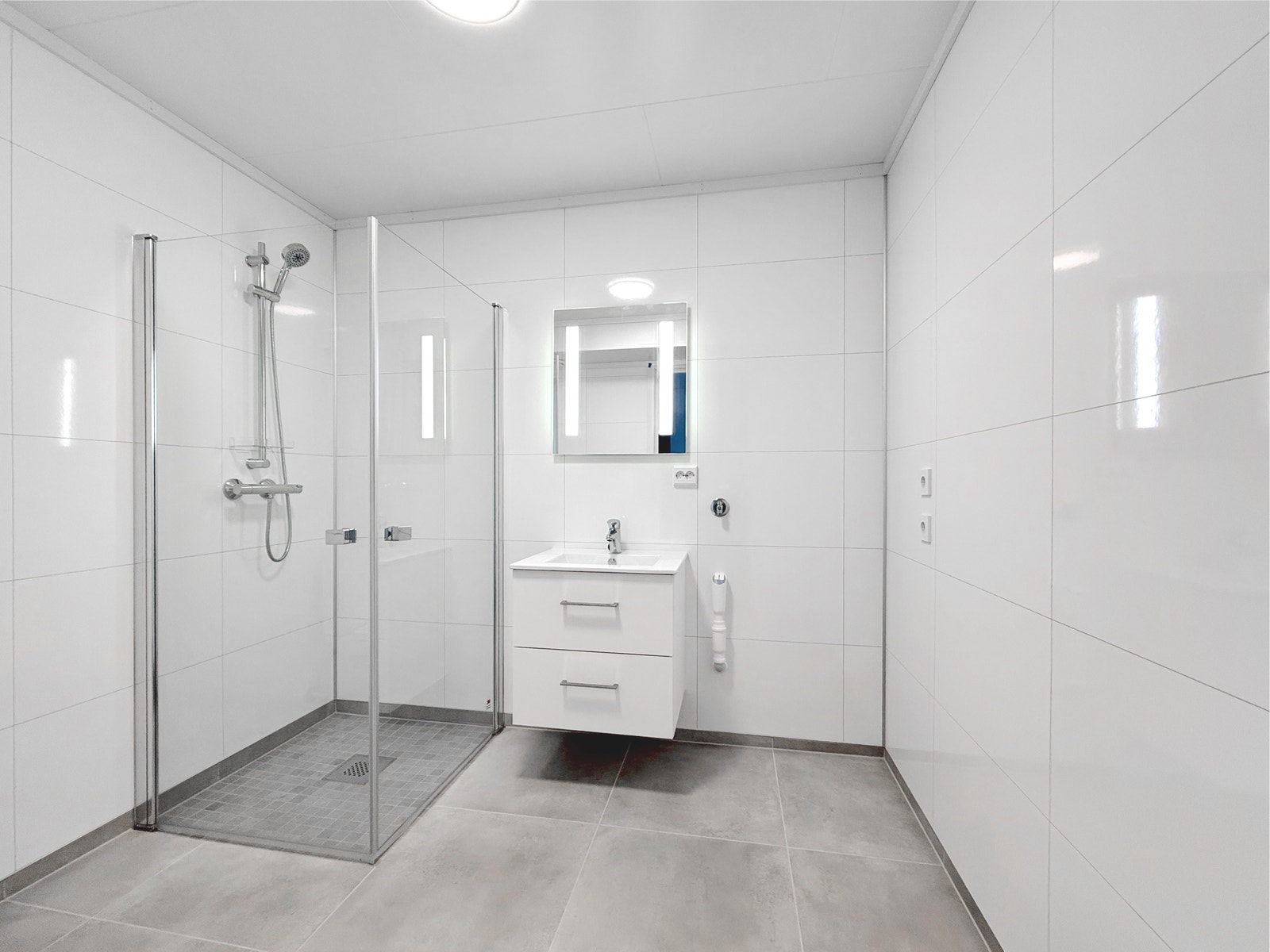 Flislagt bad med dusjhjørne, vegghengt servant med praktisk underskap og opplegg for vaskemaskin Galleribilde