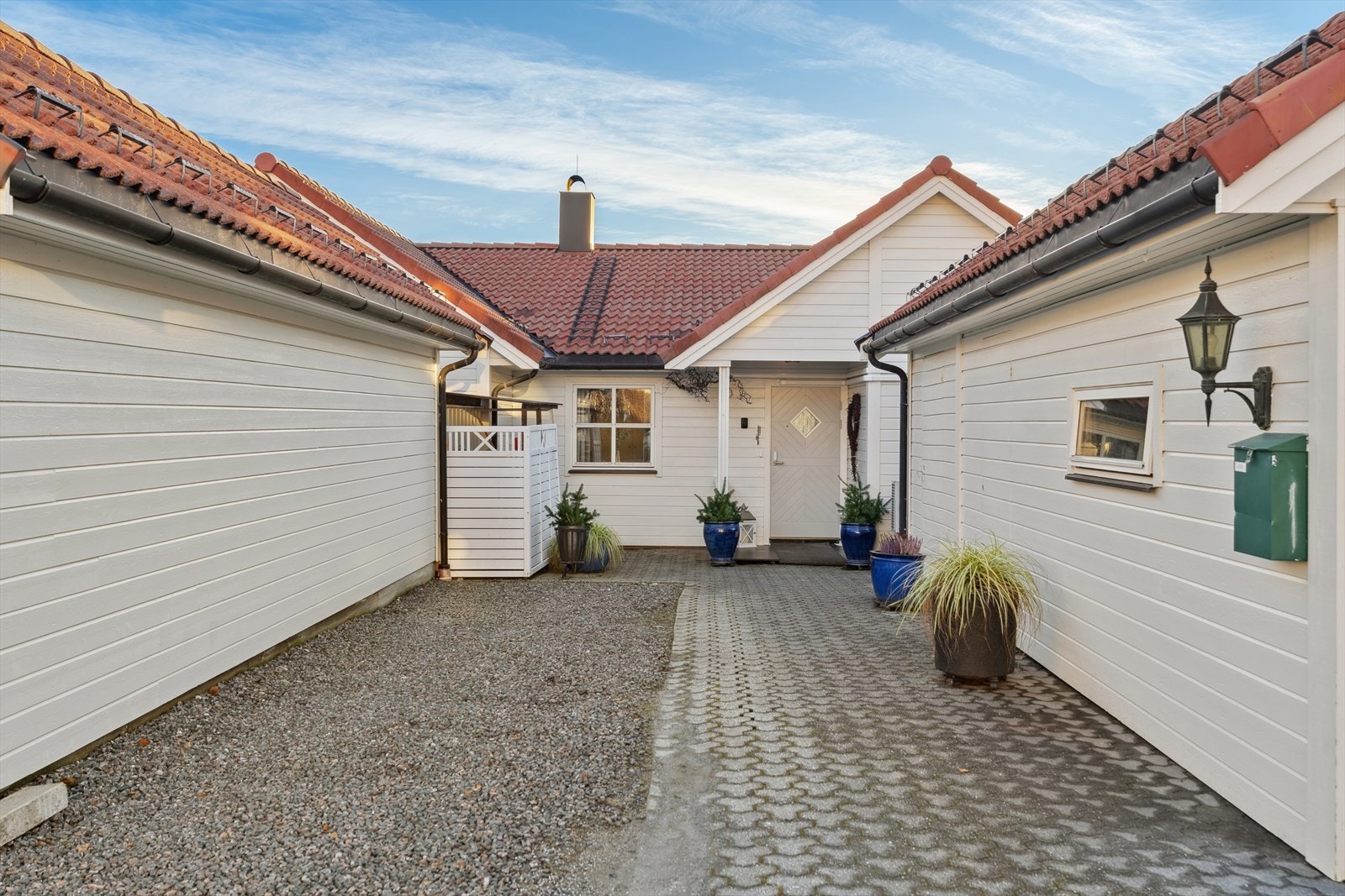 Hovedinngangen rammes inn av en garasje og med brostein som gir et pent og solid dekke. Dette gir et ryddig og innbydende førsteinntrykk, samtidig som det gir enkel tilgang til lagringsplass og parkering rett ved inngangspartiet. Galleribilde