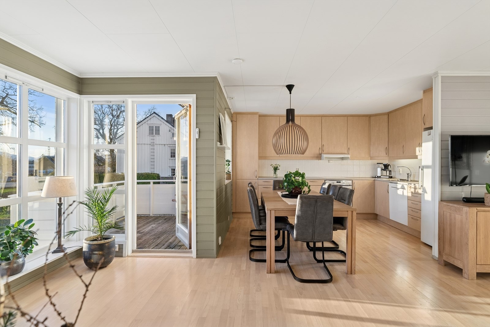 Den åpne løsningen mellom stue og kjøkken gir en naturlig og innbydende spiseplass, perfekt for hyggelige måltider og sosialt samvær. Galleribilde