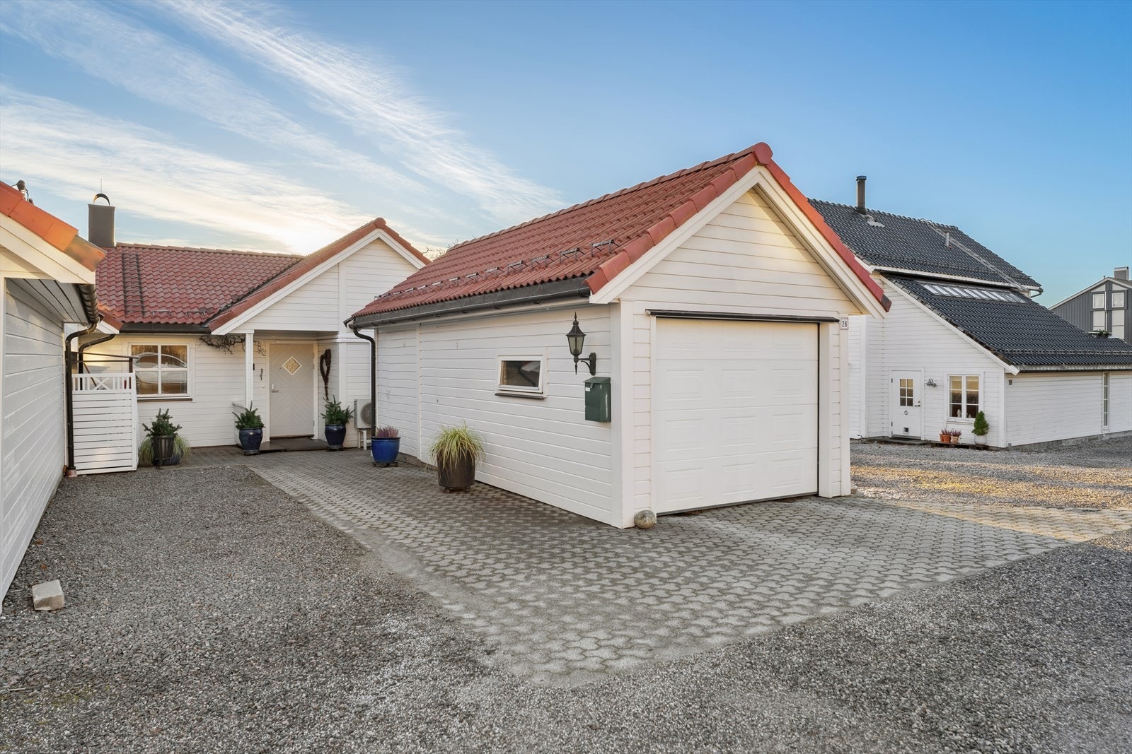 Boligen ønsker deg velkommen med et pent, overbygget inngangsparti som gir et godt førsteinntrykk og praktisk beskyttelse mot vær og vind. Herfra har du enkel tilgang til garasjen med elbillader og tilhørende bod. Galleribilde