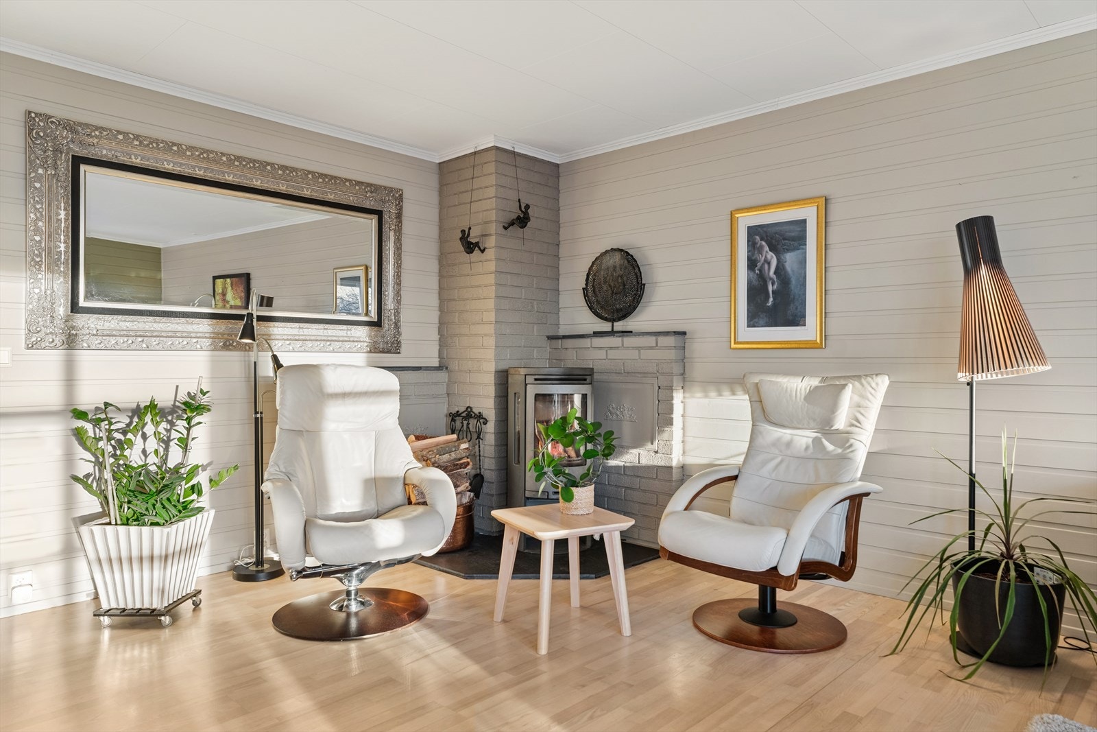 Lys stue med parkettgulv og panelvegger skaper et komfortabelt oppholdsrom. Galleribilde