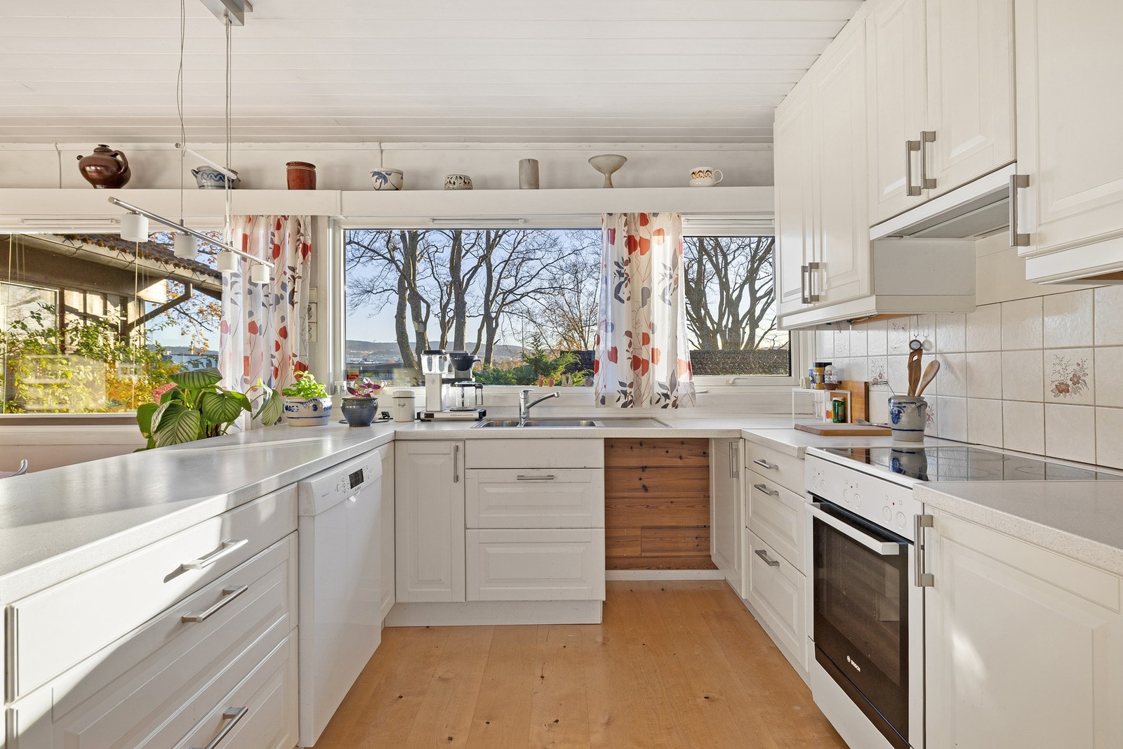 Videre er det godt med skap og benkeplass på kjøkkenet. Legg merke til de store vindusflatene som både gir fin utsikt og skaper en lys og behagelig atmosfære i kjøkkensonen. Galleribilde