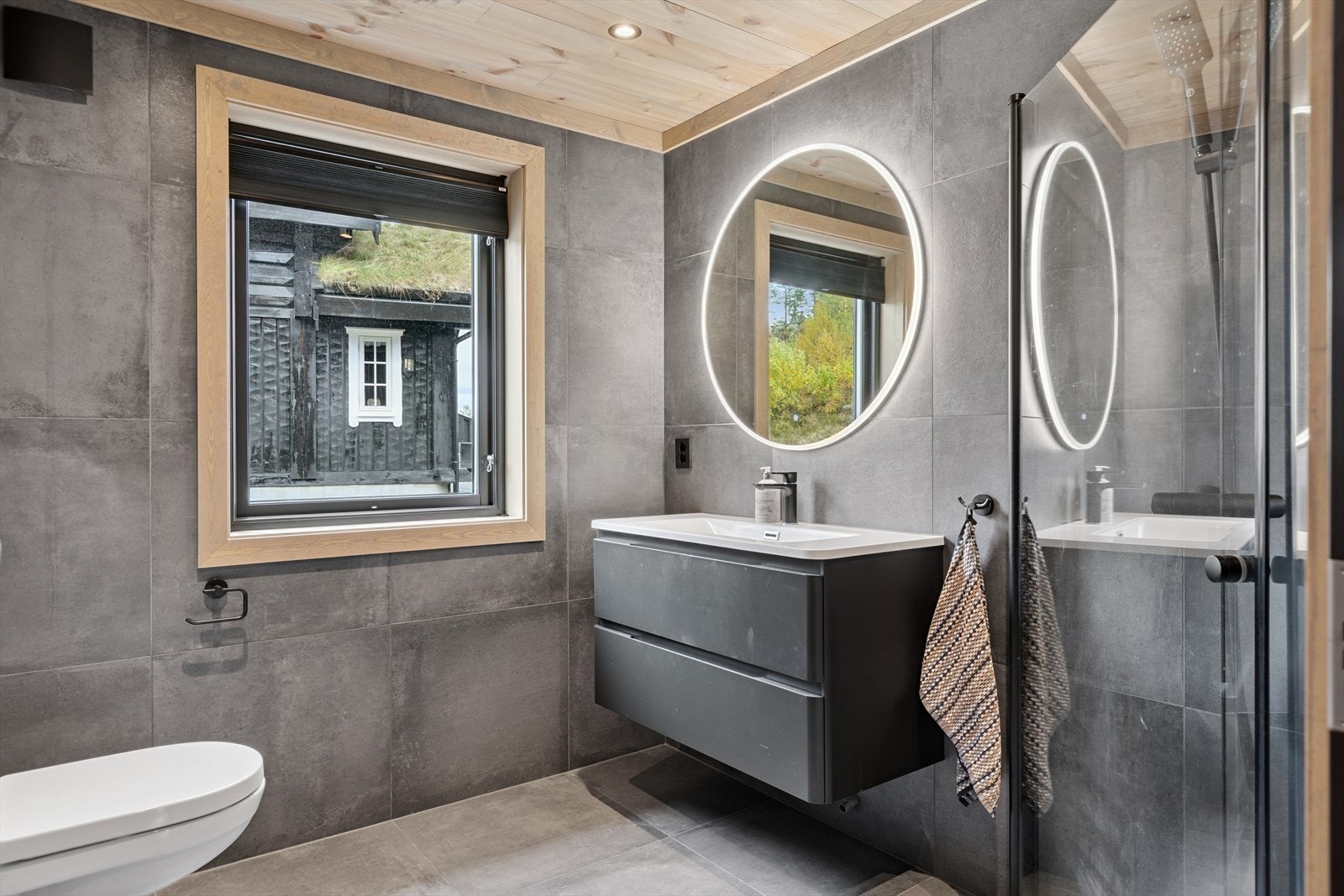 Stilfullt bad i 1. etg med vegghengt wc, dusjhjørne med innfellbare dører og regnfalldusj samt servantskap med stort speil med lys. Galleribilde