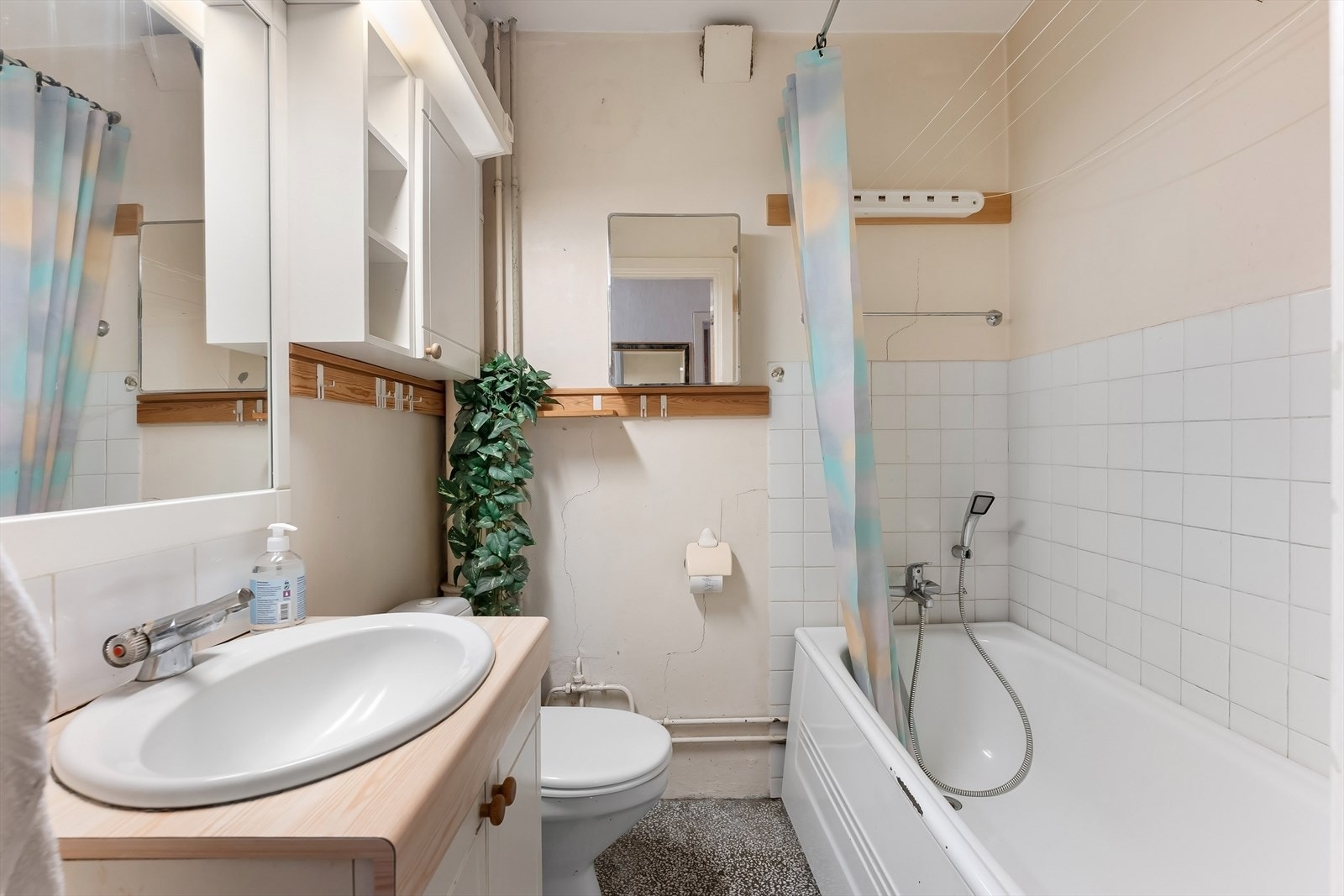 Eldre bad med behov for oppussing. Badekar, toalett, servantinnredning og speilskap. Galleribilde