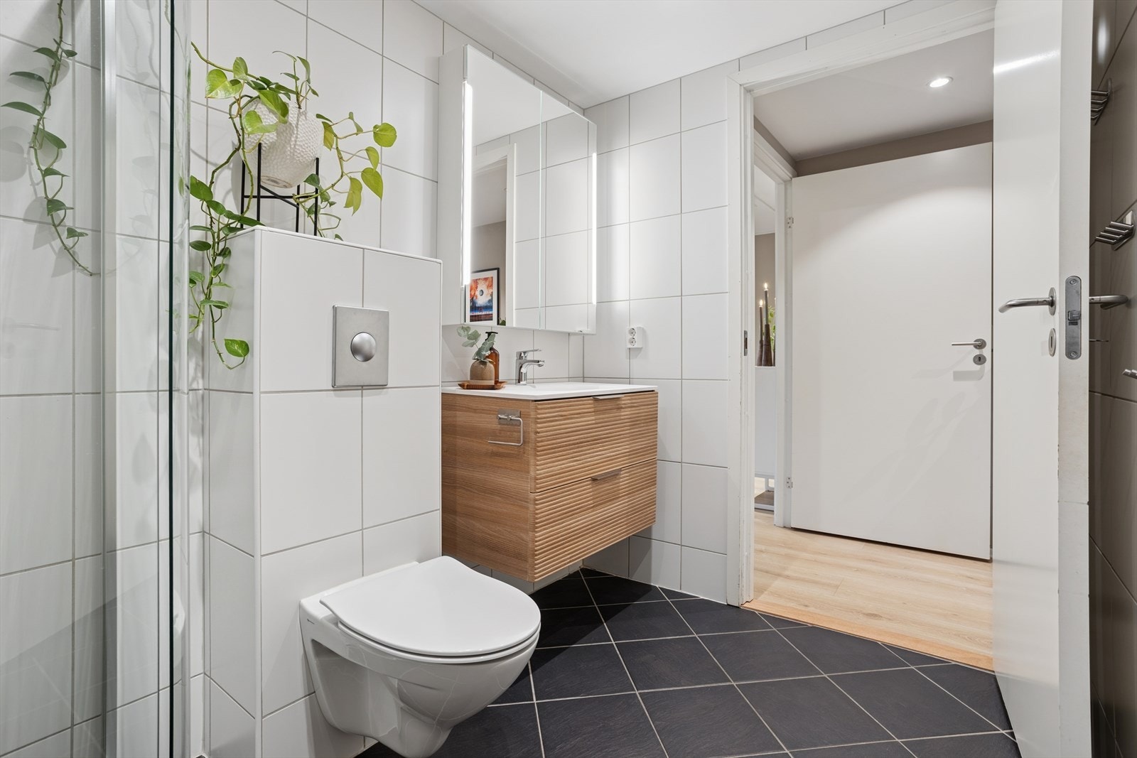 Innredningen består av et nytt møblement med servant fra 2025, overskap med speilfelt og integrert lys, samt et vegghengt toalett med innebygd sisterne. Videre finnes et dusjhjørne med glassdører. Galleribilde