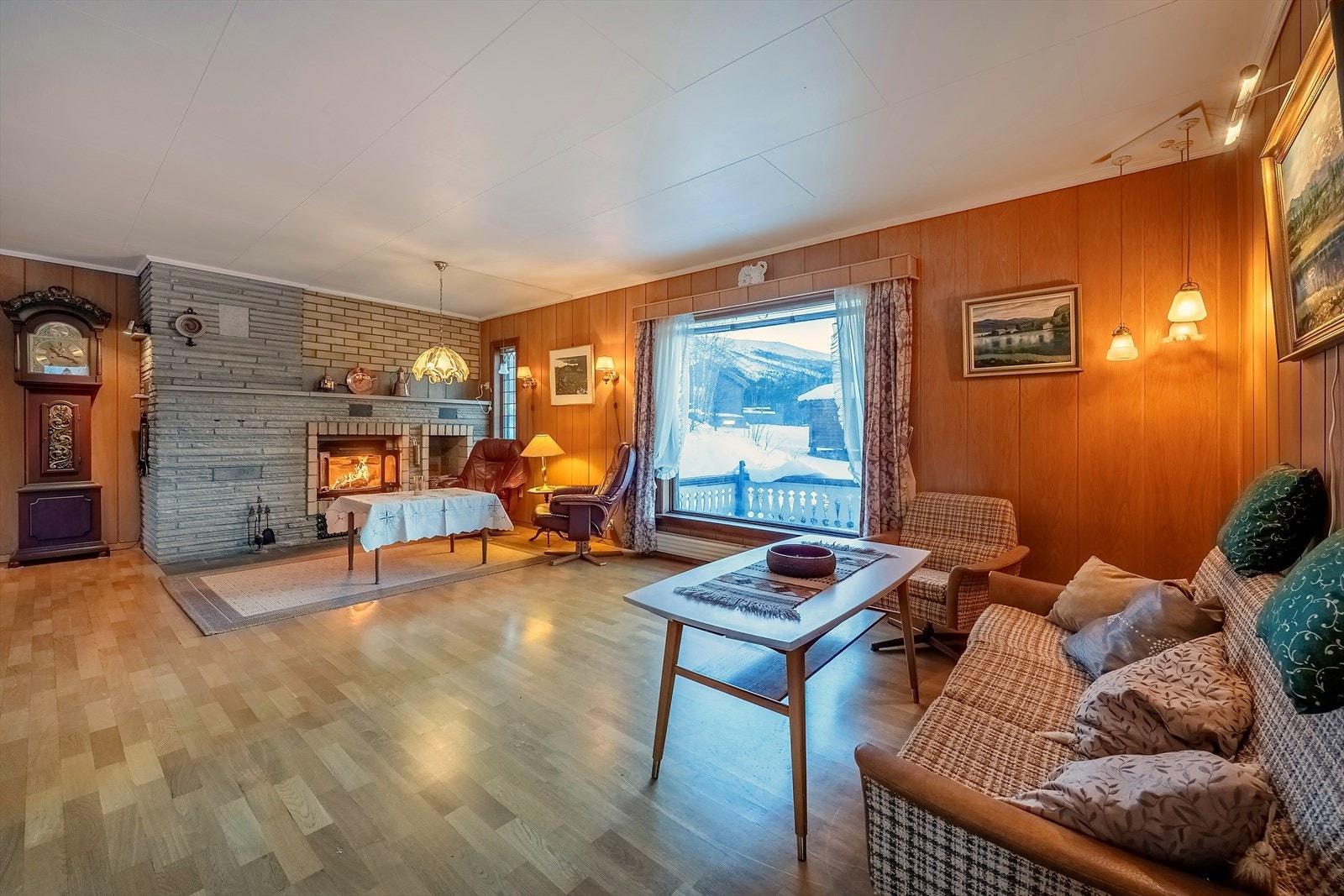 Stua har murt peis i skifer og tegl med peisinnsats og vednisje Galleribilde